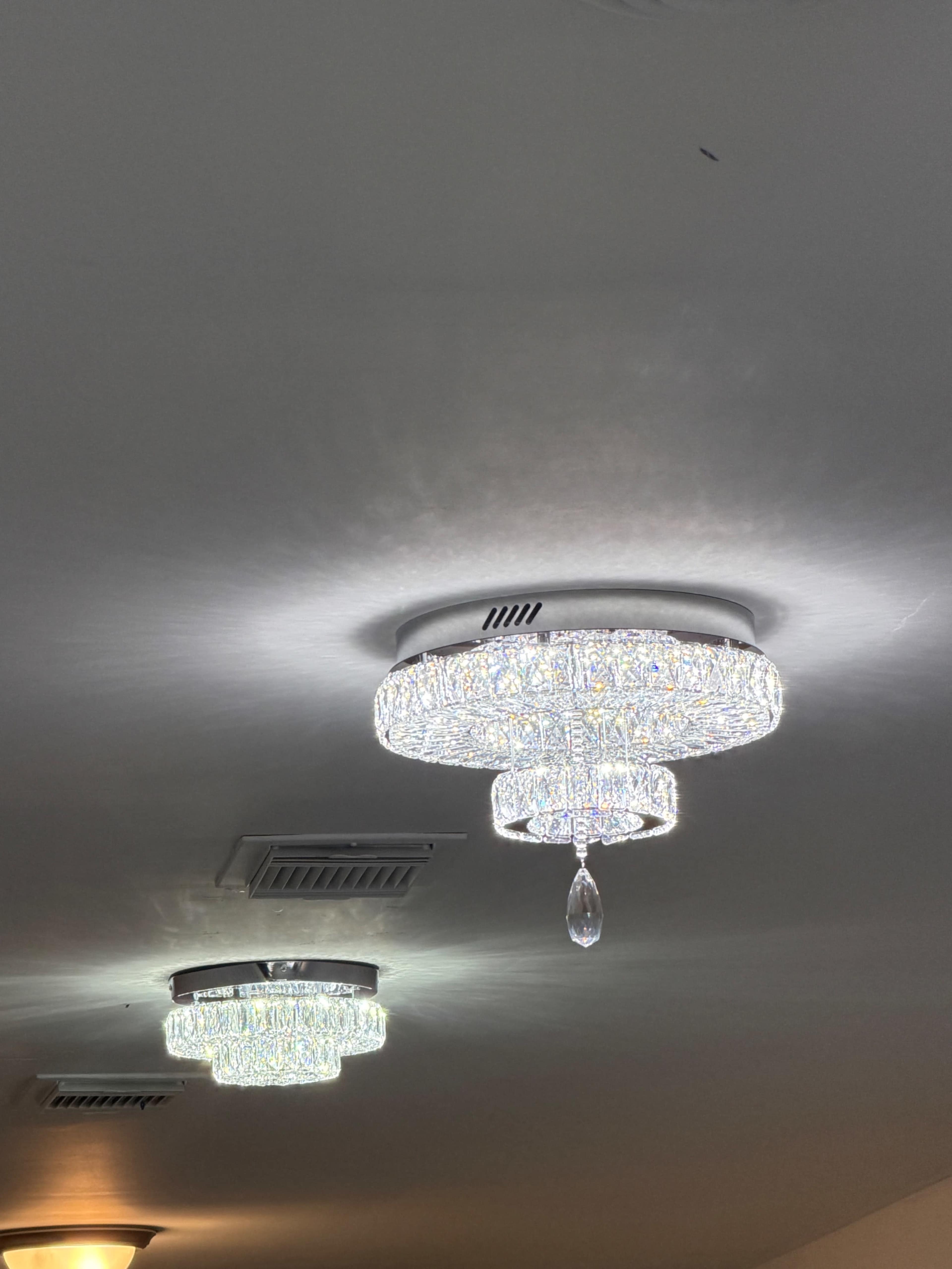 Two decorative ceiling lights, resembling chandeliers, are mounted on the ceiling with a crystal design and emit bright reflections.