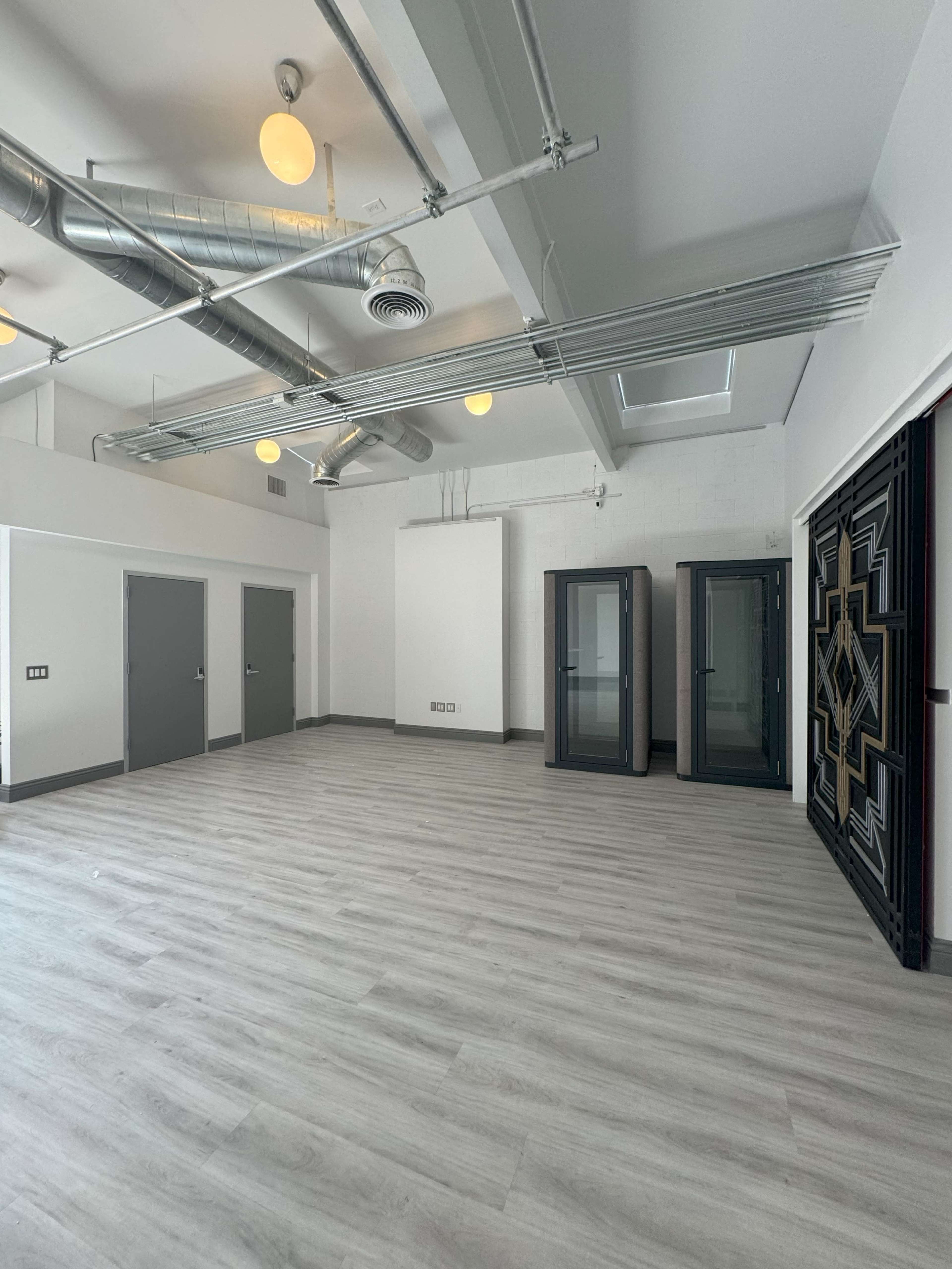 A spacious, modern room with light wood flooring, gray doors, and large glass display cabinets along one wall.