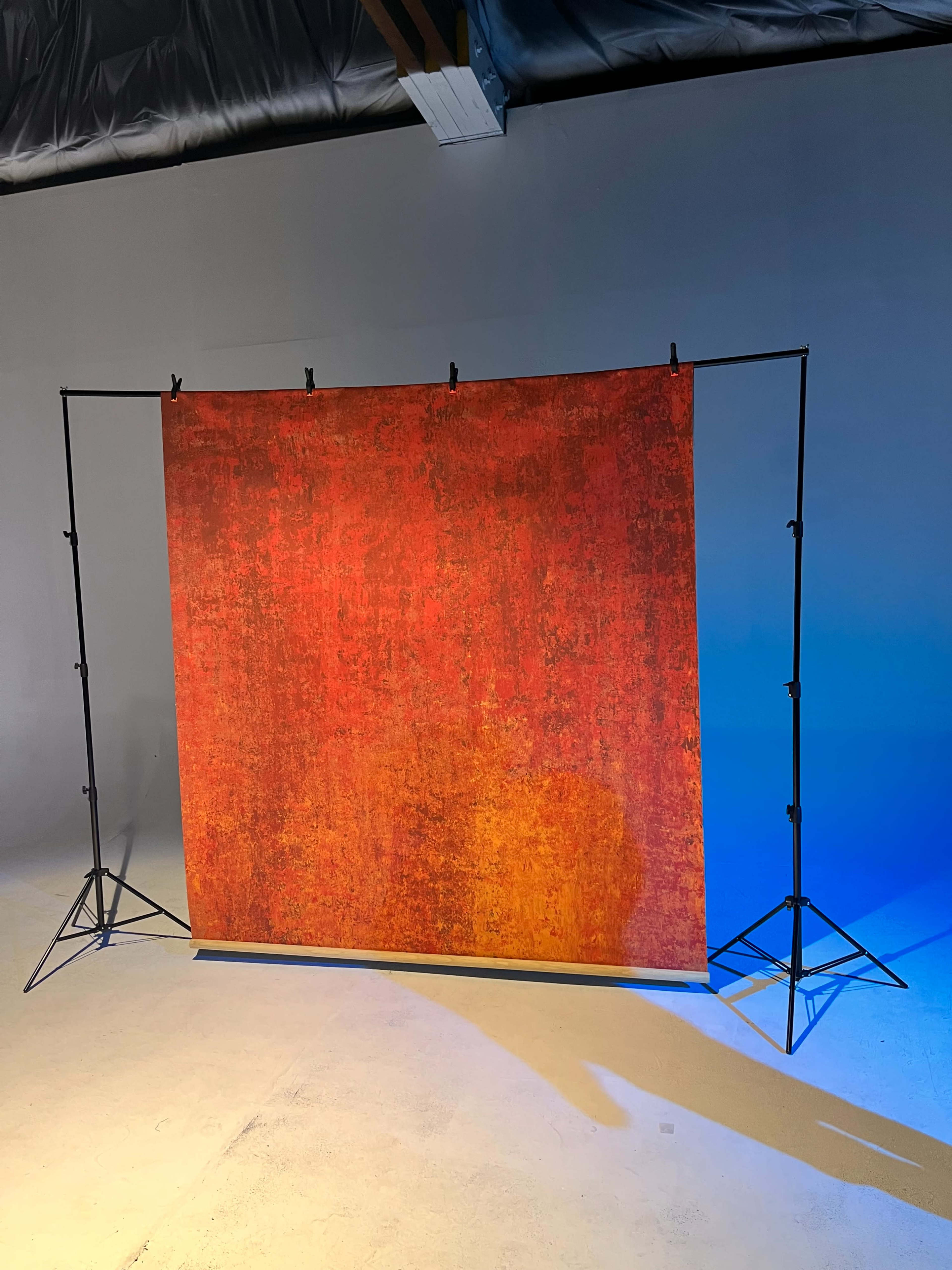 The image shows a textured red backdrop set up on a black support frame, illuminated by blue light.