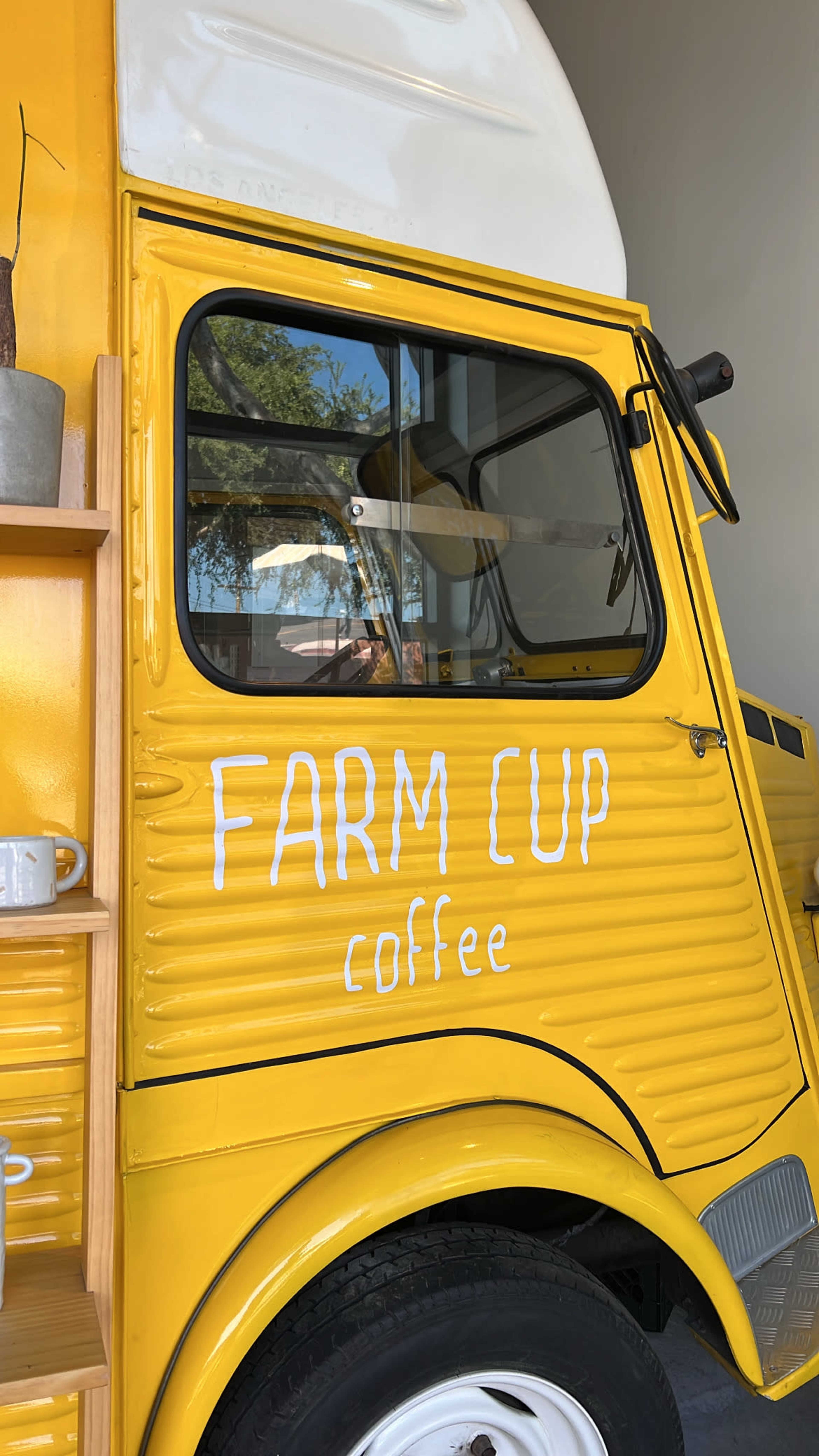 A bright yellow coffee truck with the words "FARM CUP coffee" is parked inside a building.