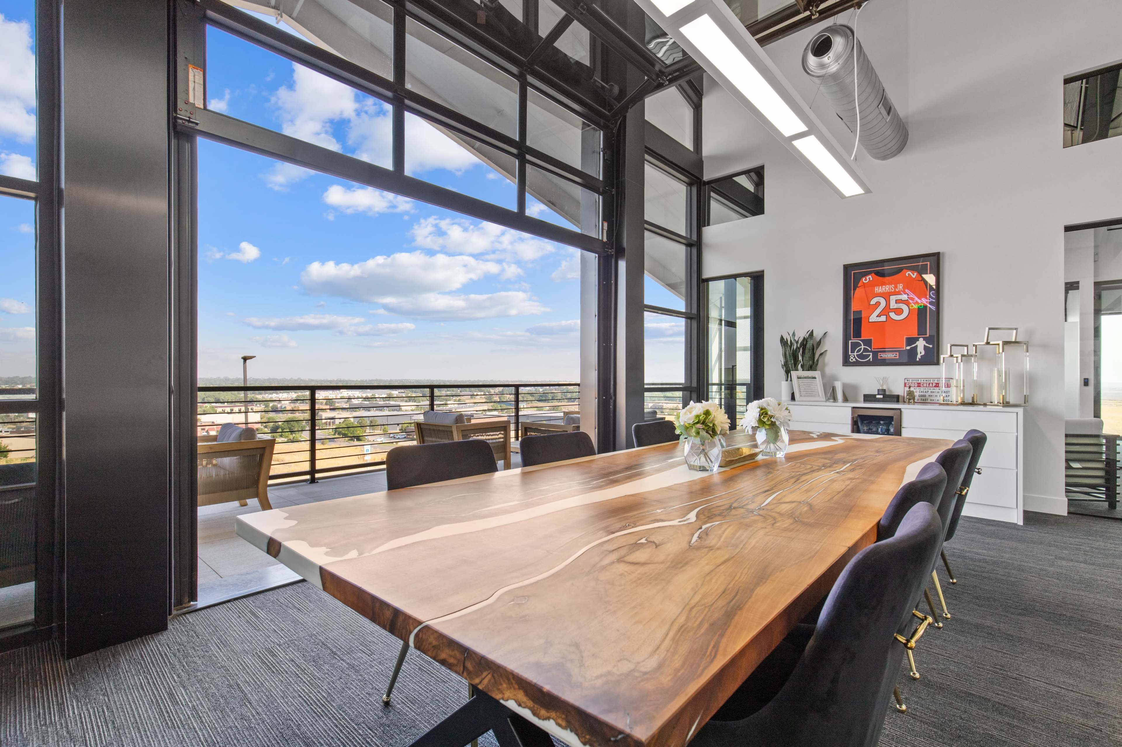 A large wooden conference table is positioned in a modern meeting room with floor-to-ceiling windows offering a view of the city skyline.