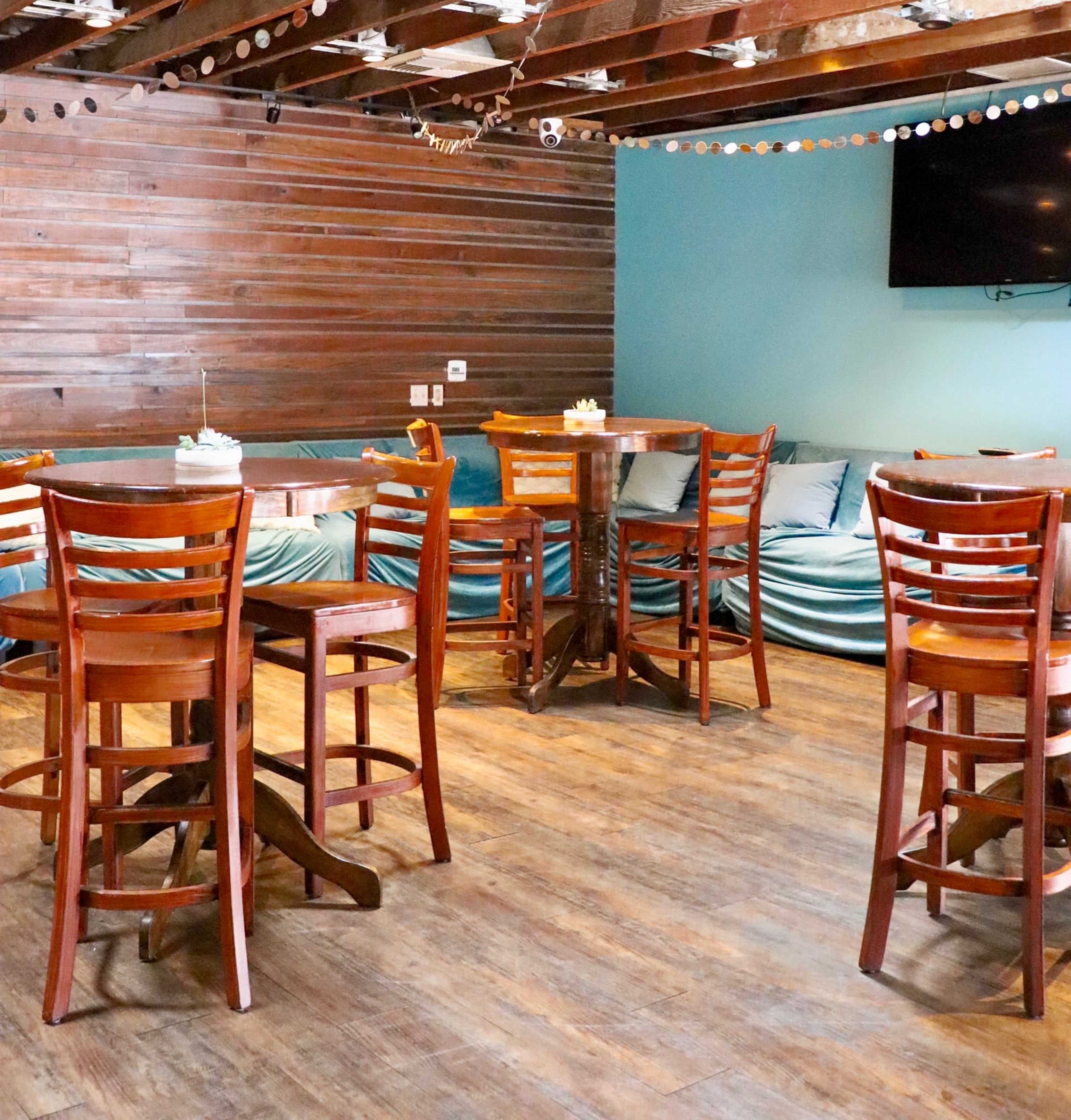 A seating area in a restaurant with wooden tables and chairs arranged against a wooden-paneled wall.