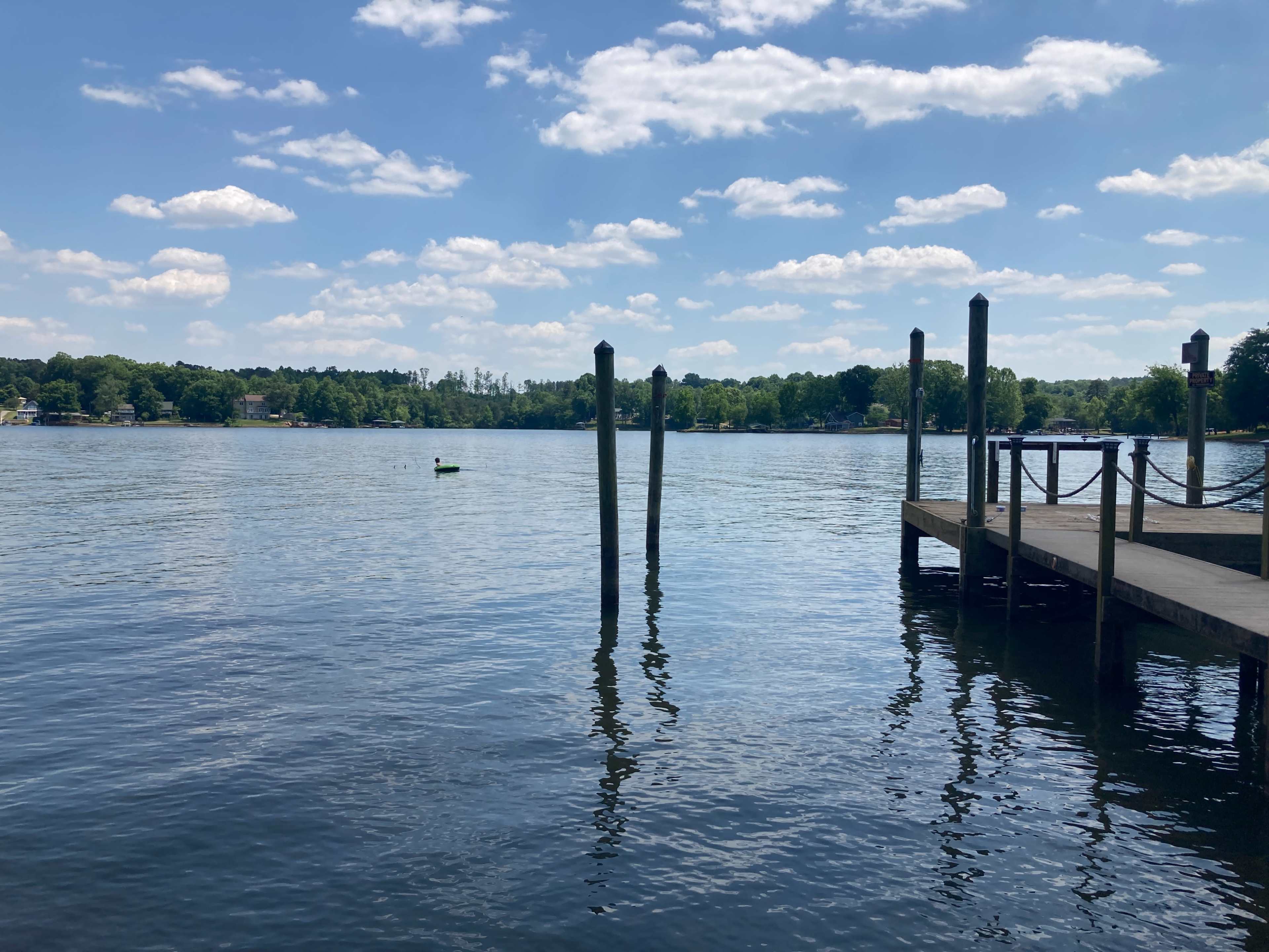 A calm lake with a wooden dock and two weathered posts extending from the water.