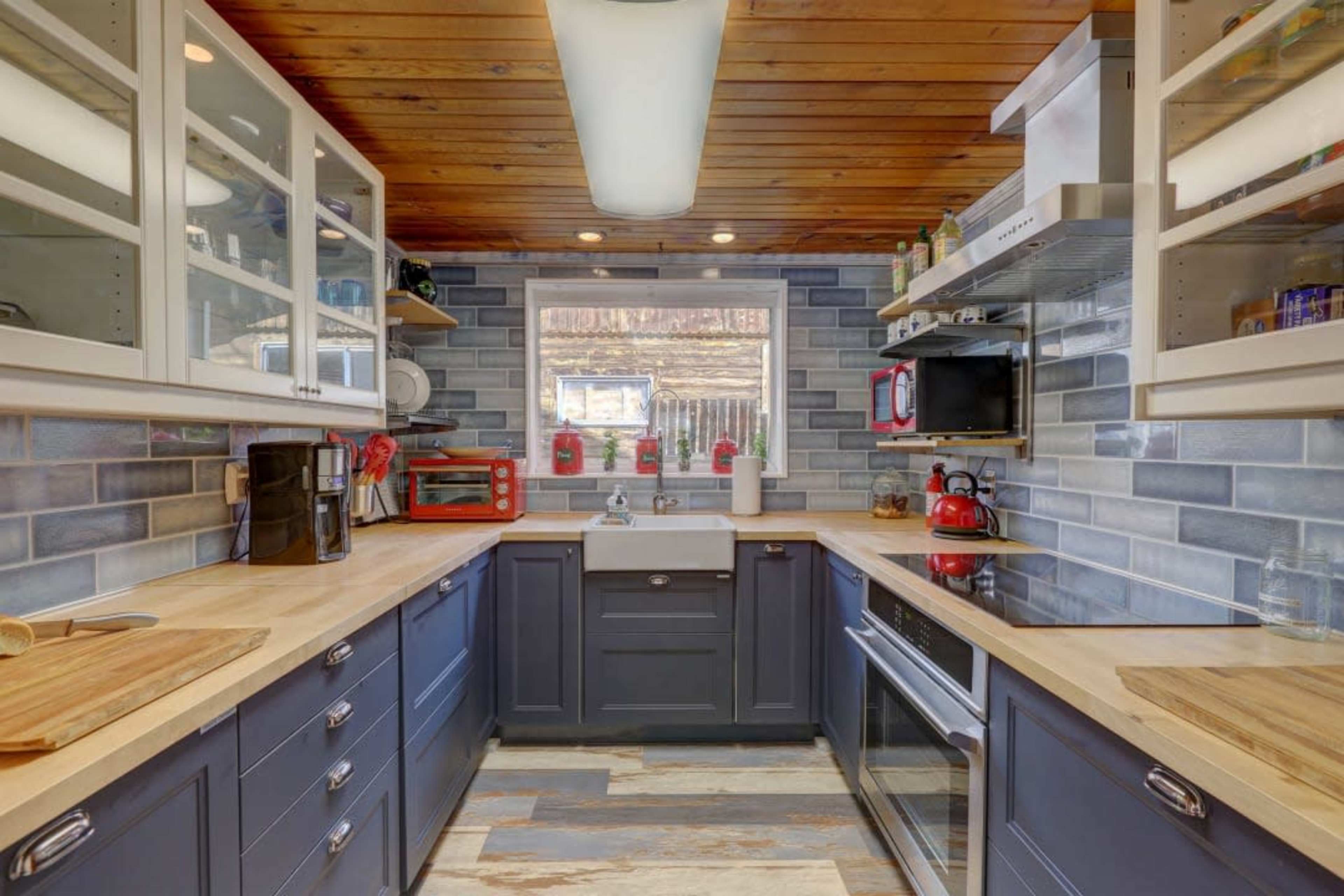 The kitchen features dark blue cabinetry, wooden countertops, and gray tiled walls with a window providing natural light.