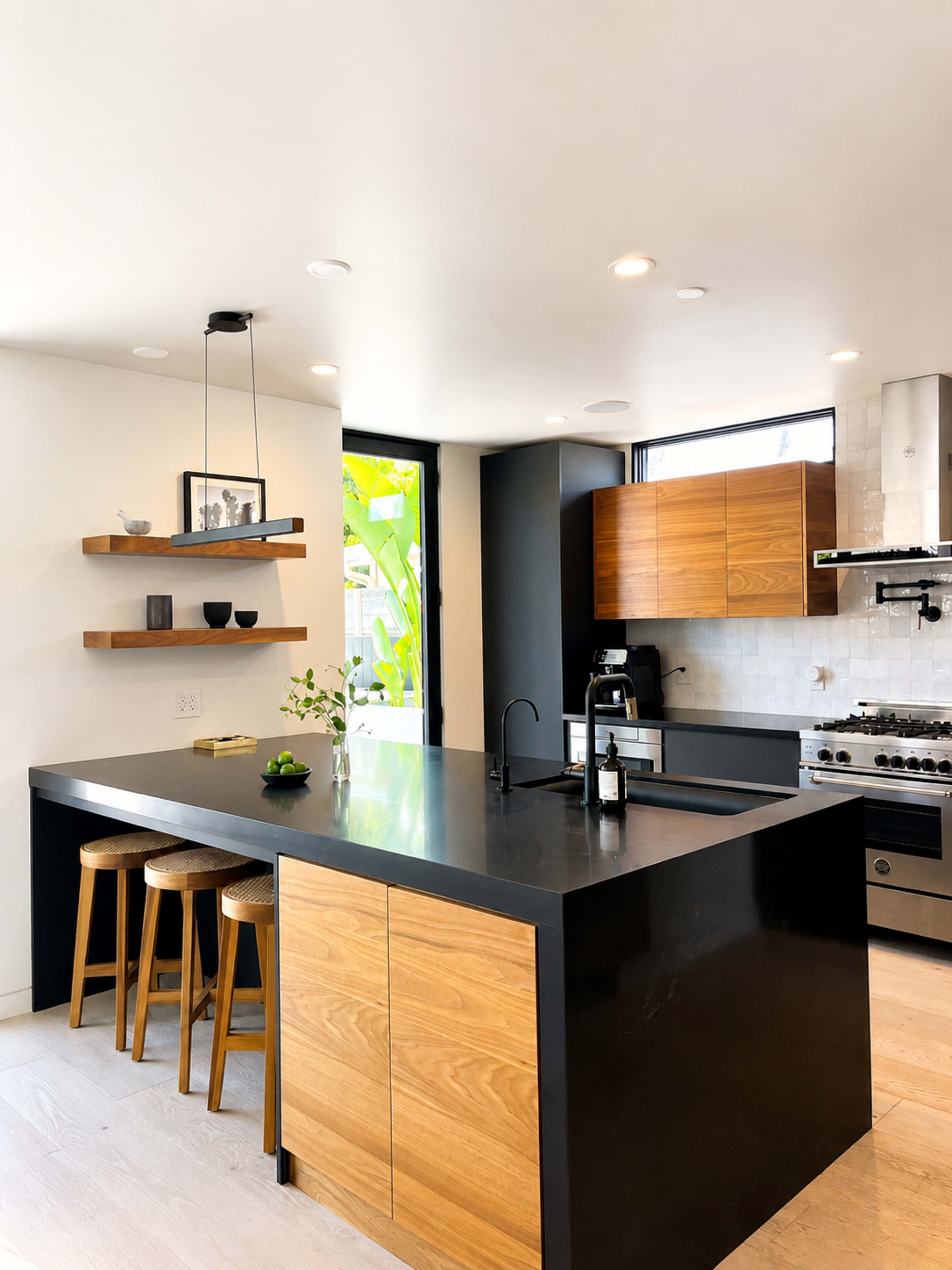 The image shows a modern kitchen with a central island featuring a black countertop, wooden cabinets, and bar stools.