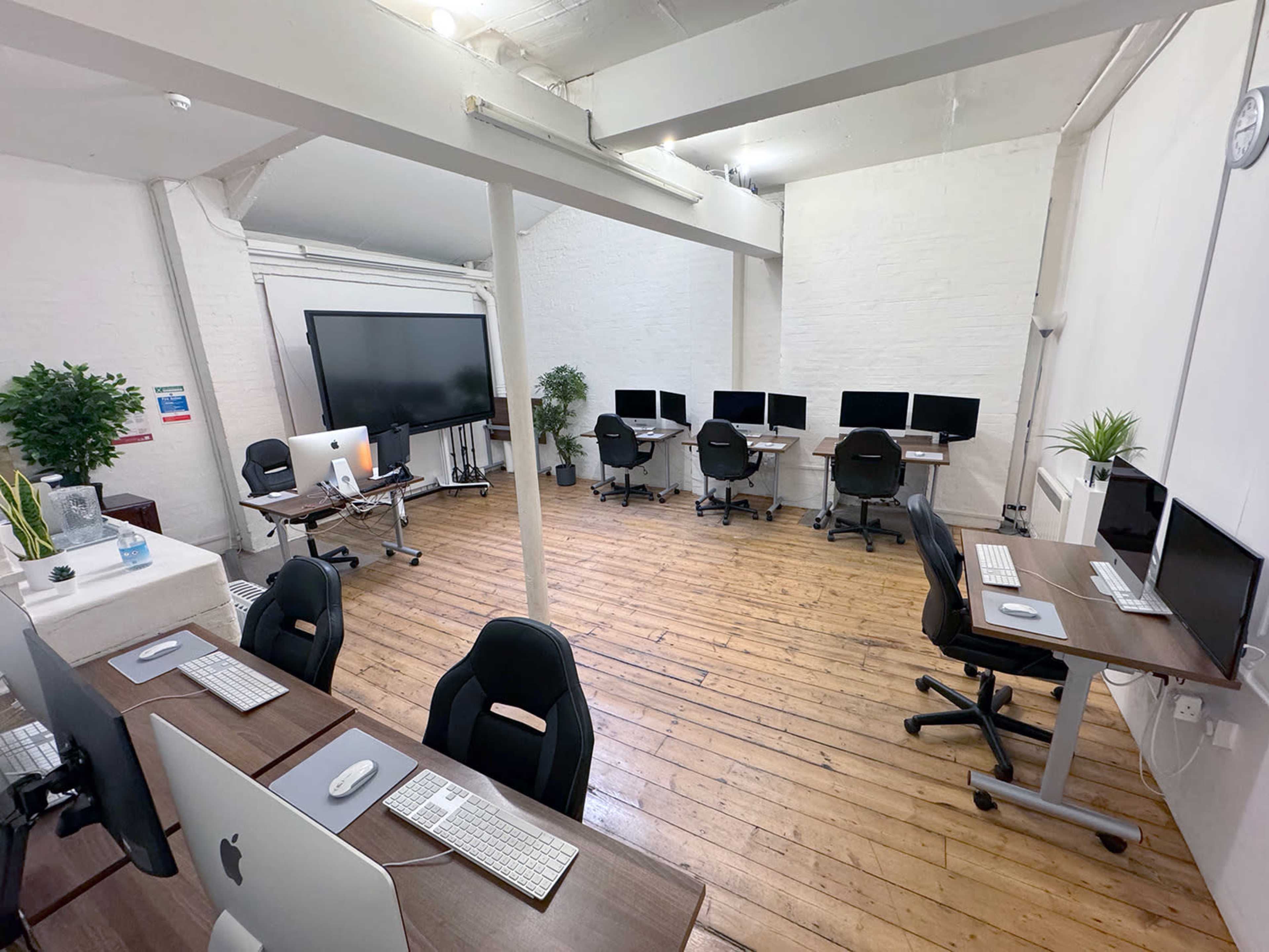 A spacious, well-lit office featuring multiple workstations with computers arranged in two separate areas.