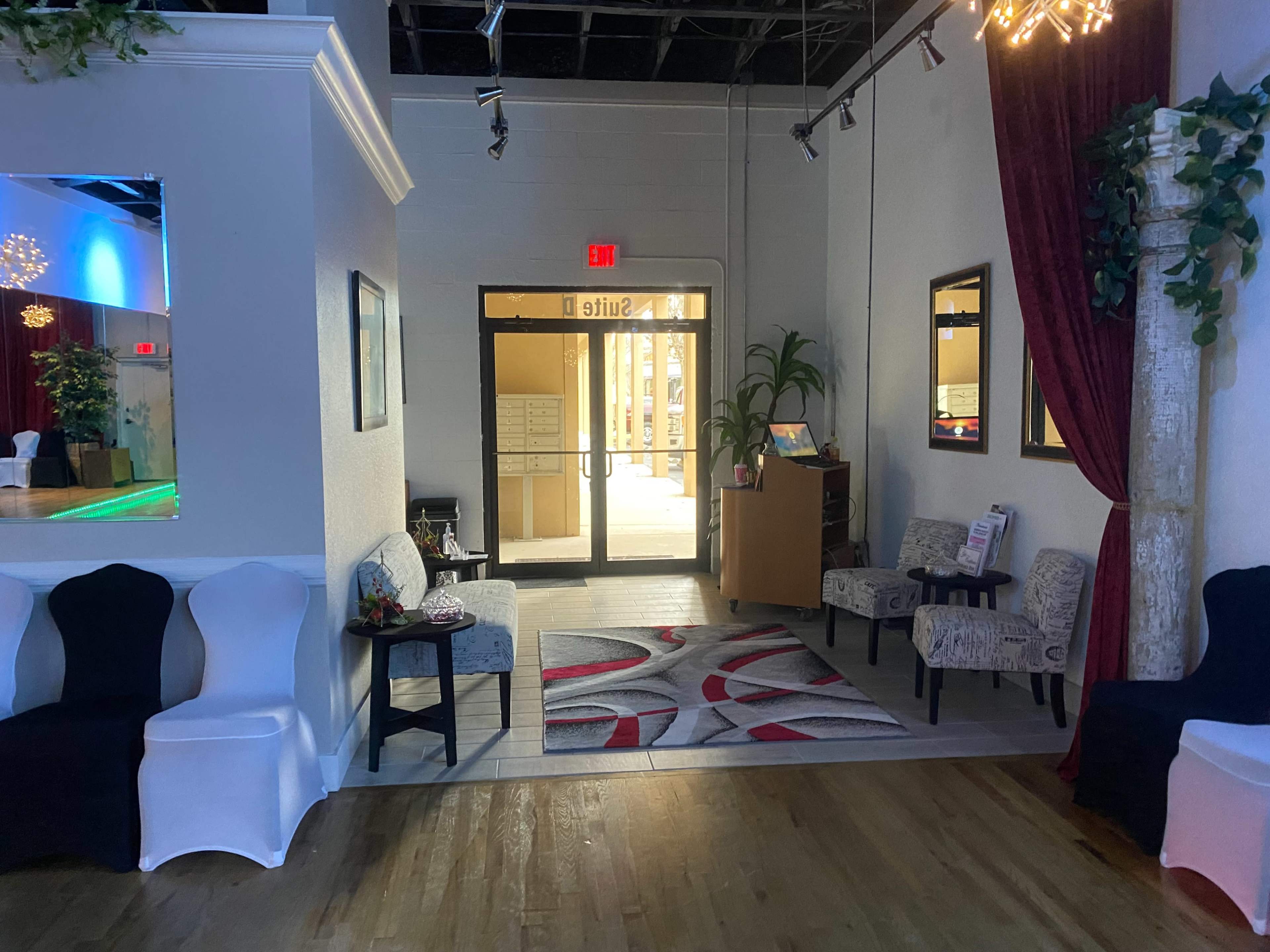 A spacious entryway with a doorway leading to a bright hallway, flanked by seating areas and decorative elements.