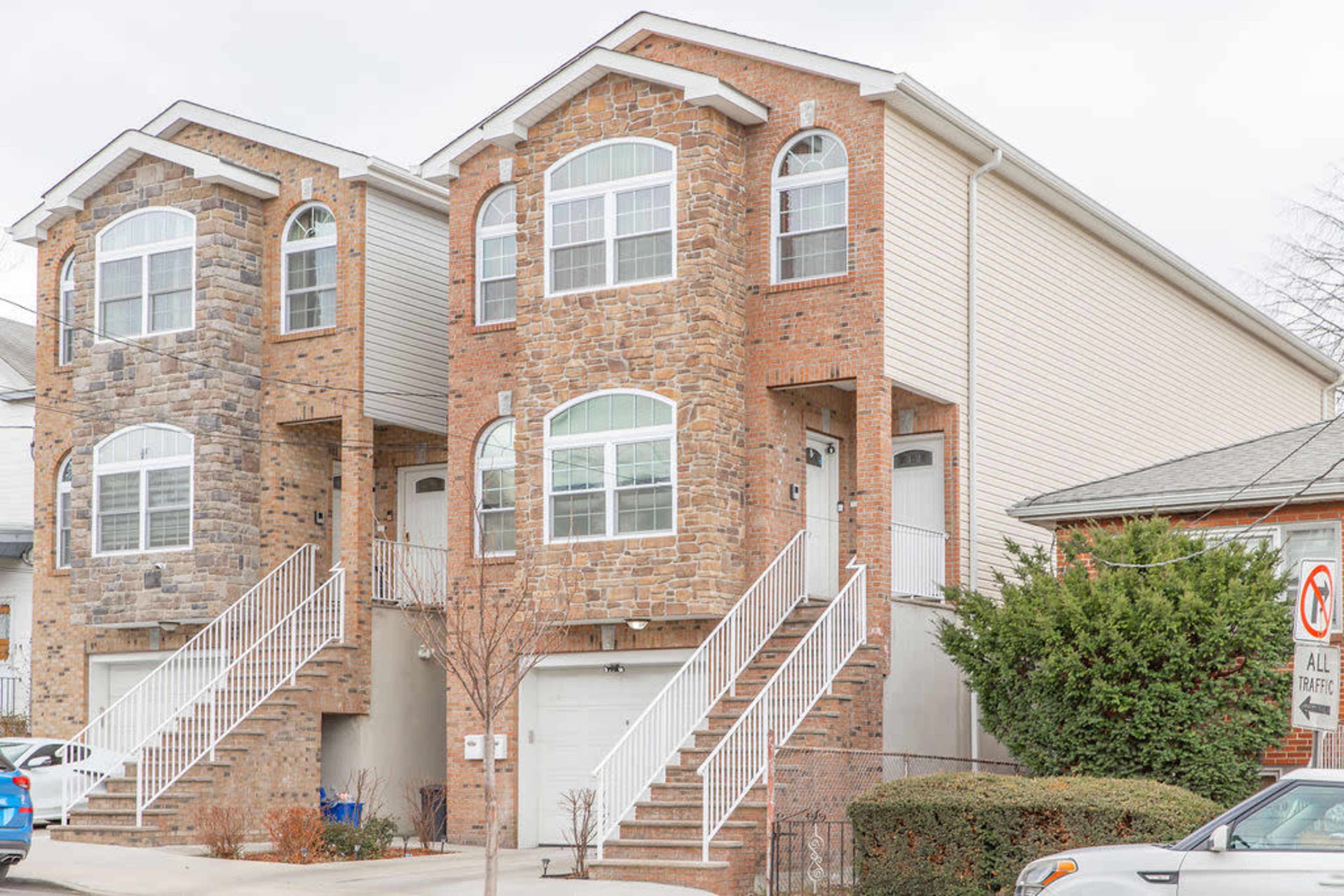 A two-family brick house with a stone facade, featuring separate entrances and staircases for each unit.