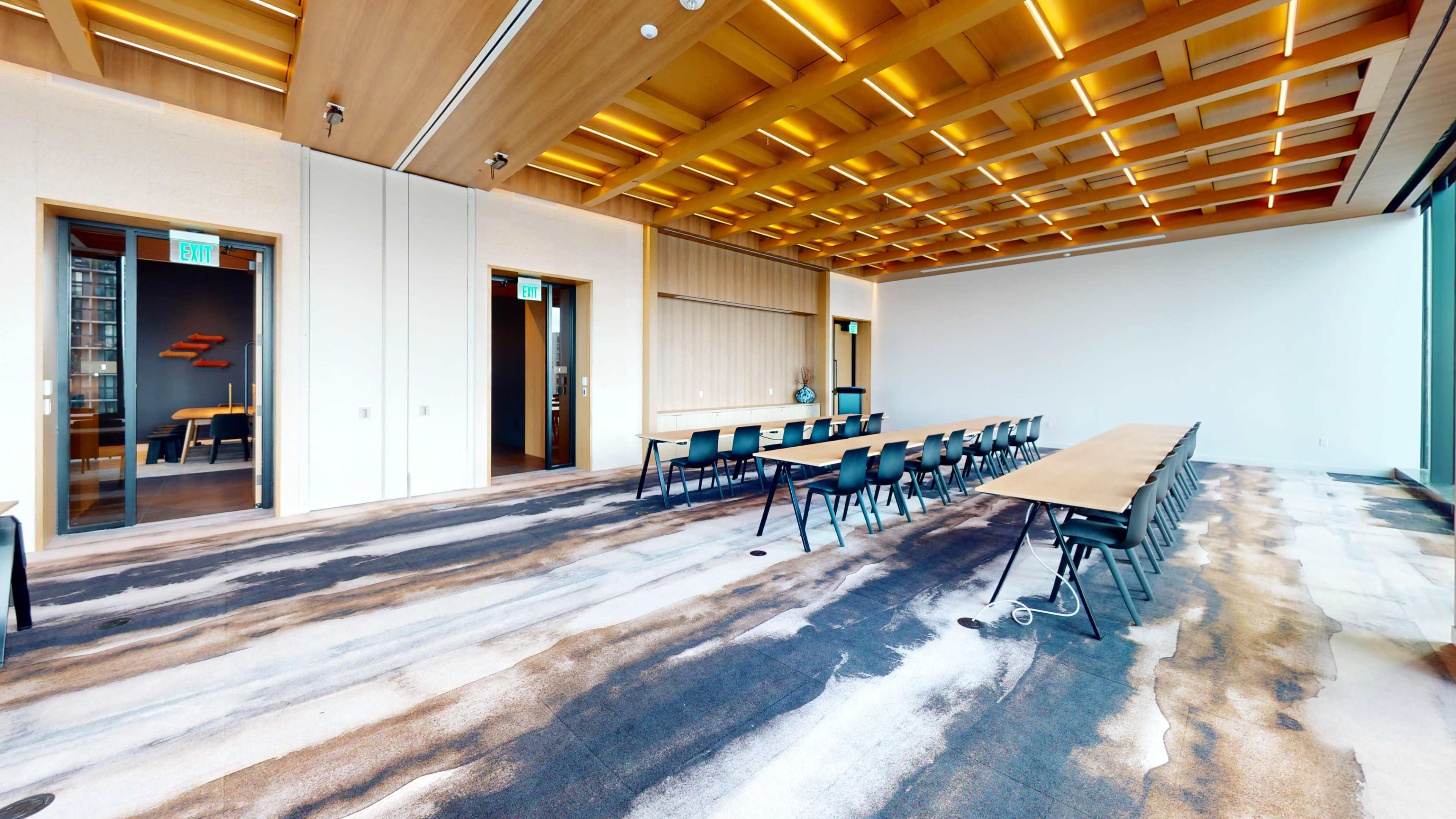 The image shows a modern conference room with a long table and black chairs, featuring wooden ceilings and large windows.