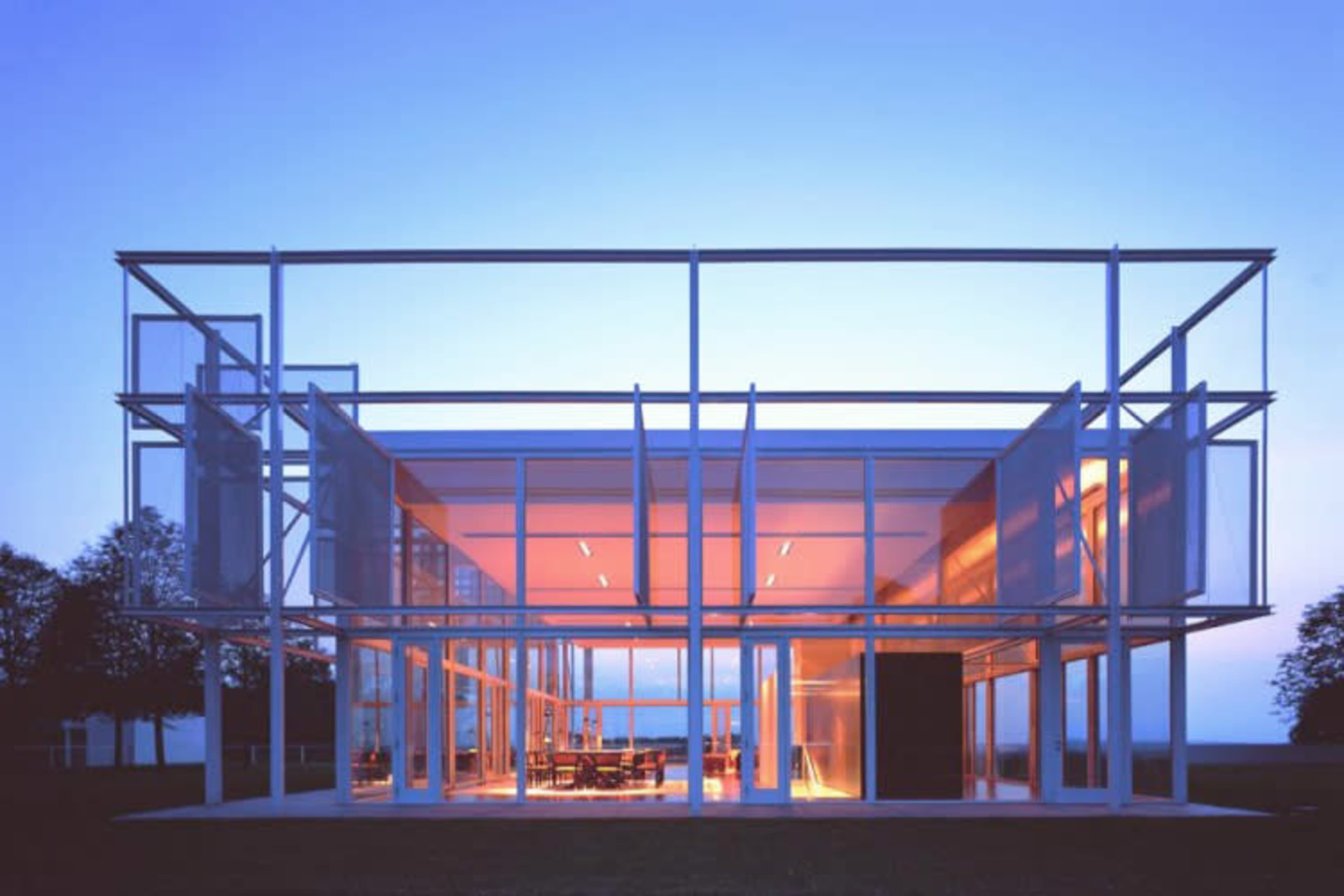A modern glass-and-steel building with a grid-like structure illuminated at dusk.