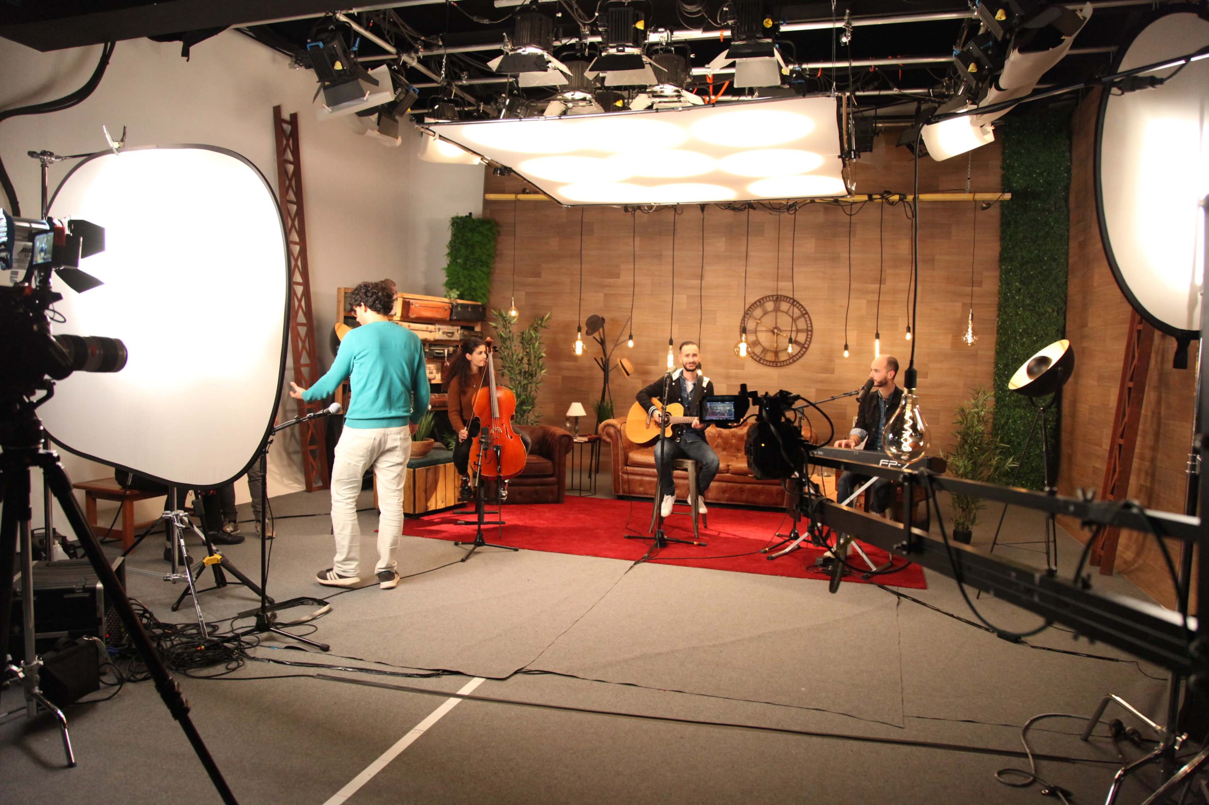 A music performance is taking place in a studio, with musicians playing instruments and recording equipment set up around them.