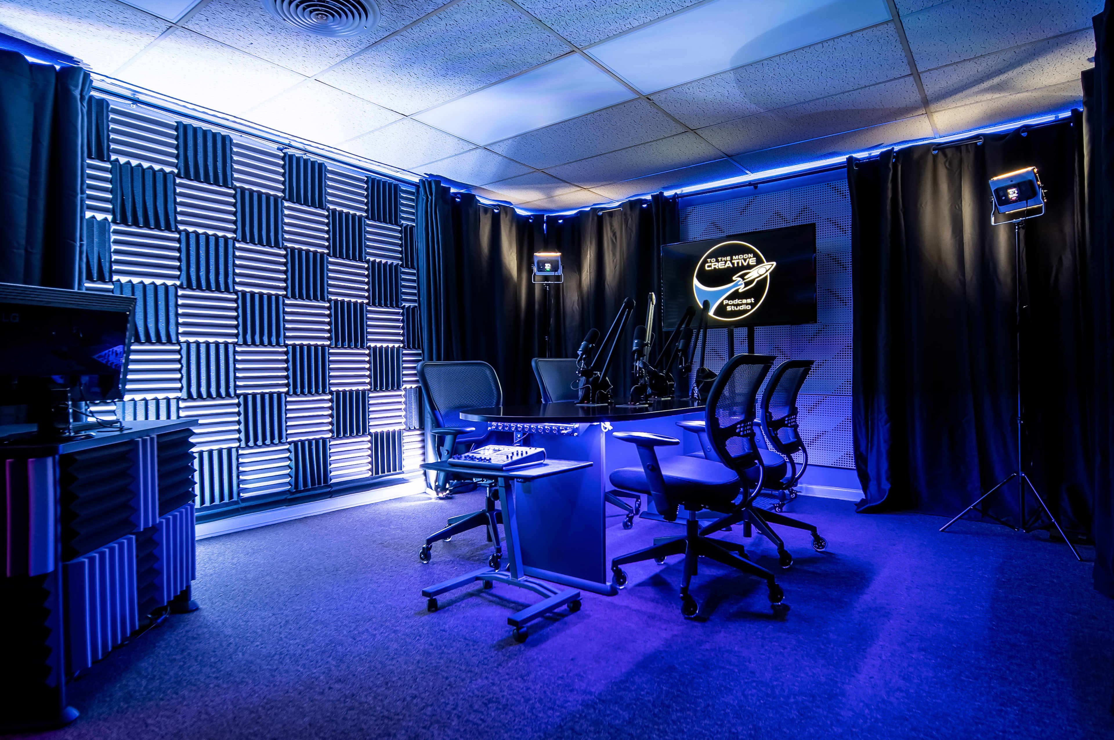 A modern podcast studio with soundproofed walls, multiple chairs, and professional lighting.