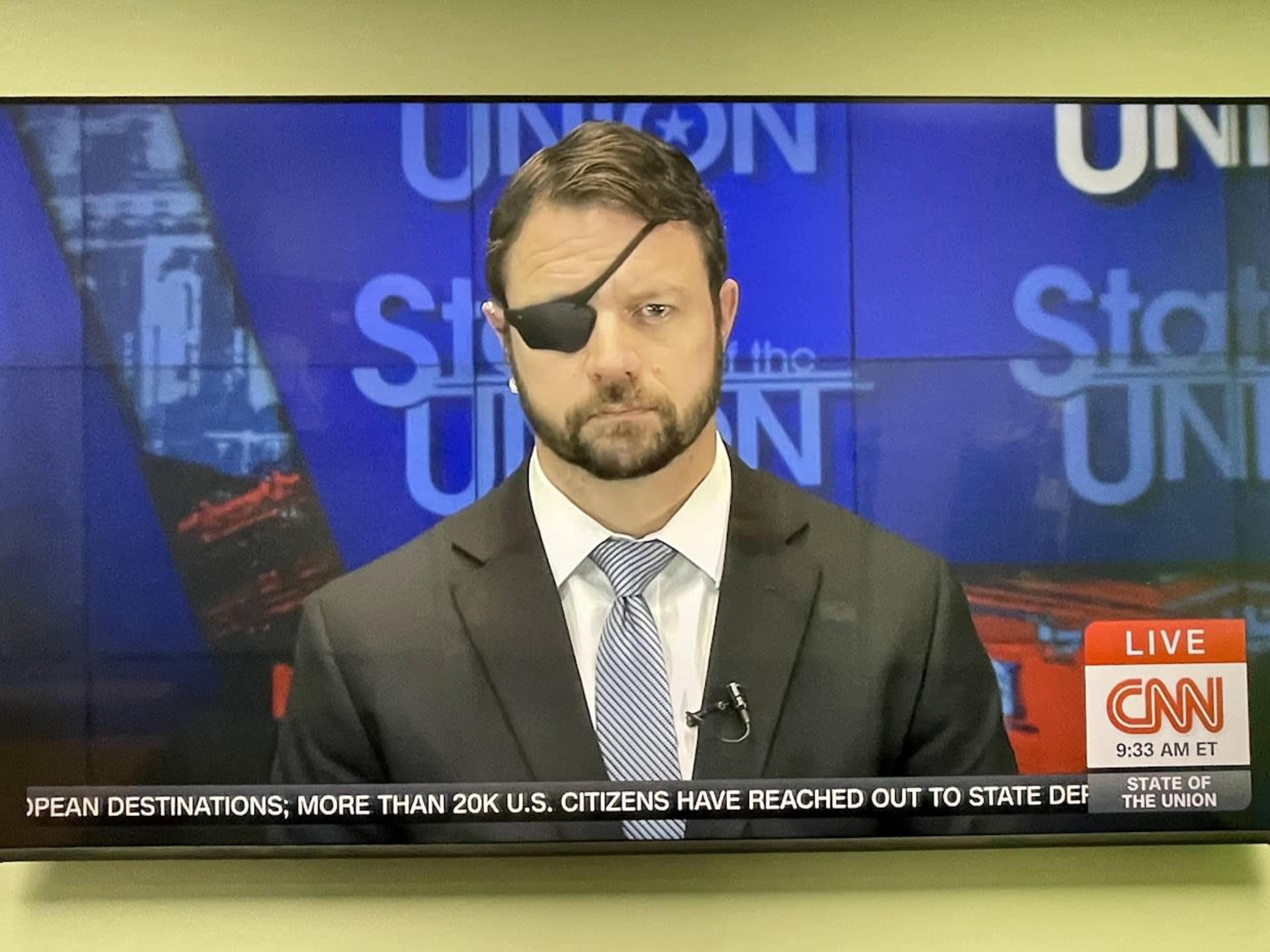 A man wearing a suit and an eye patch appears on a television screen during a live broadcast labeled "State of the Union" on CNN.