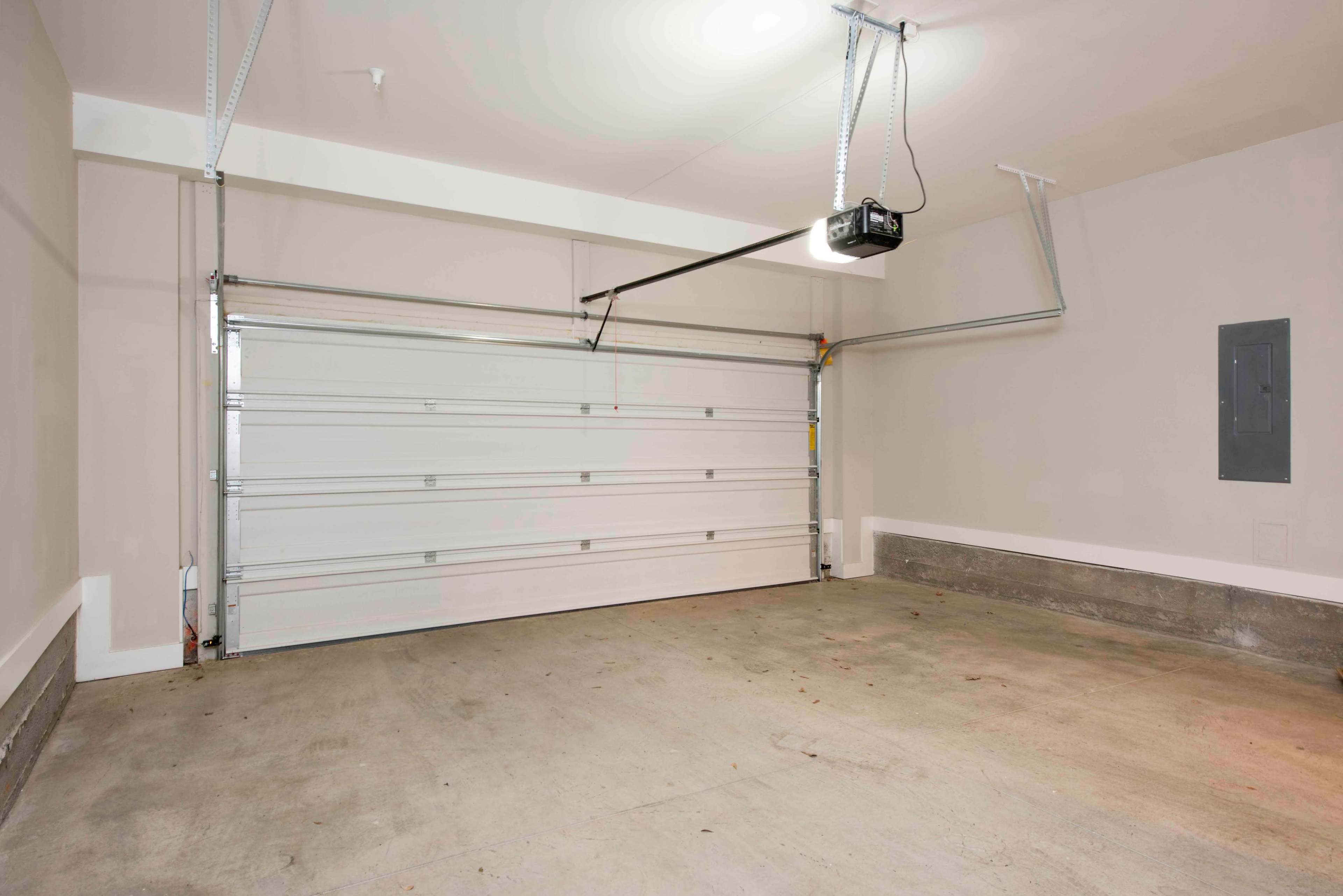 The image shows an empty garage with a closed overhead door and a light fixture installed on the ceiling.