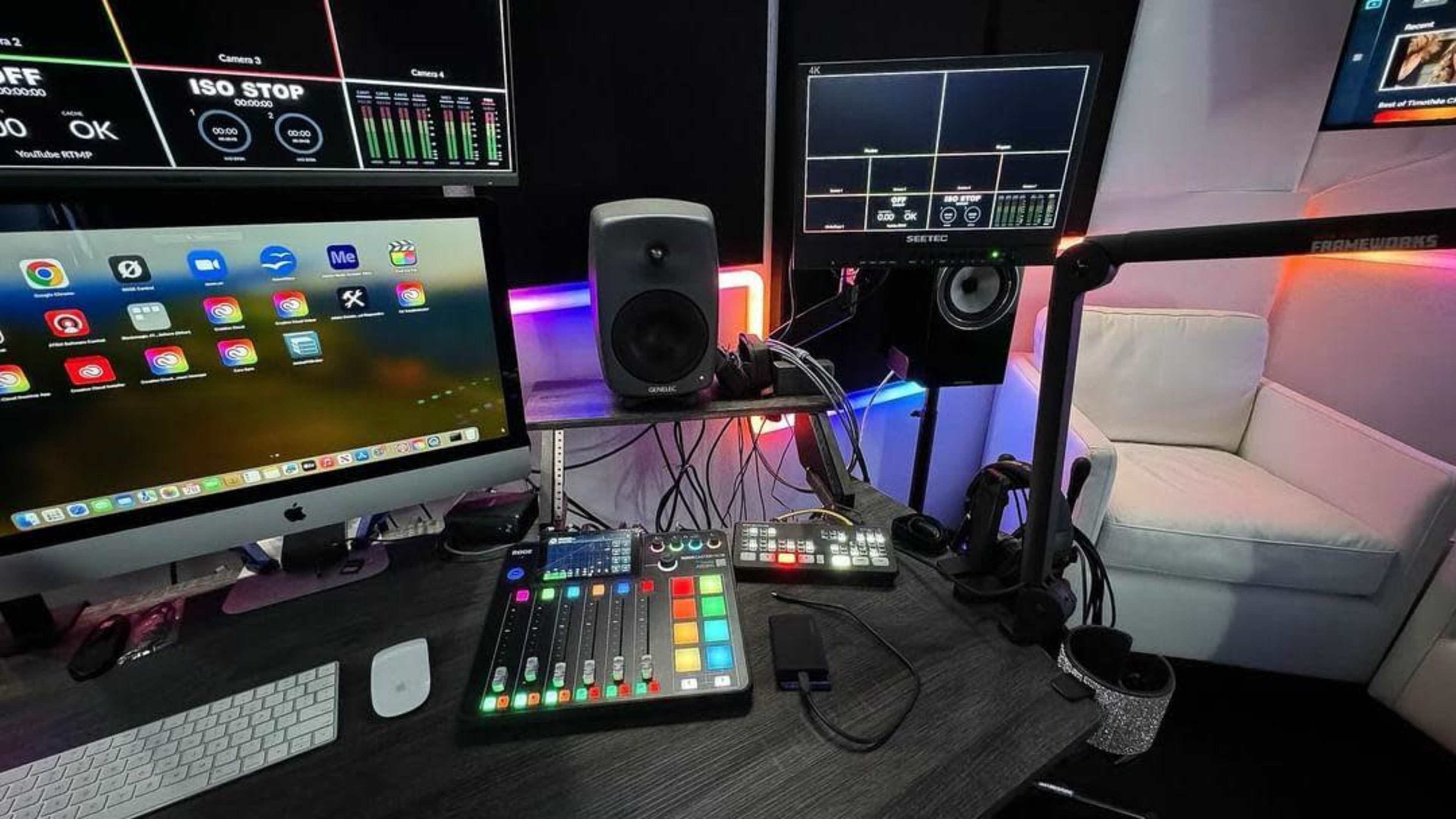 A modern media production setup featuring multiple screens, audio equipment, and a chair.