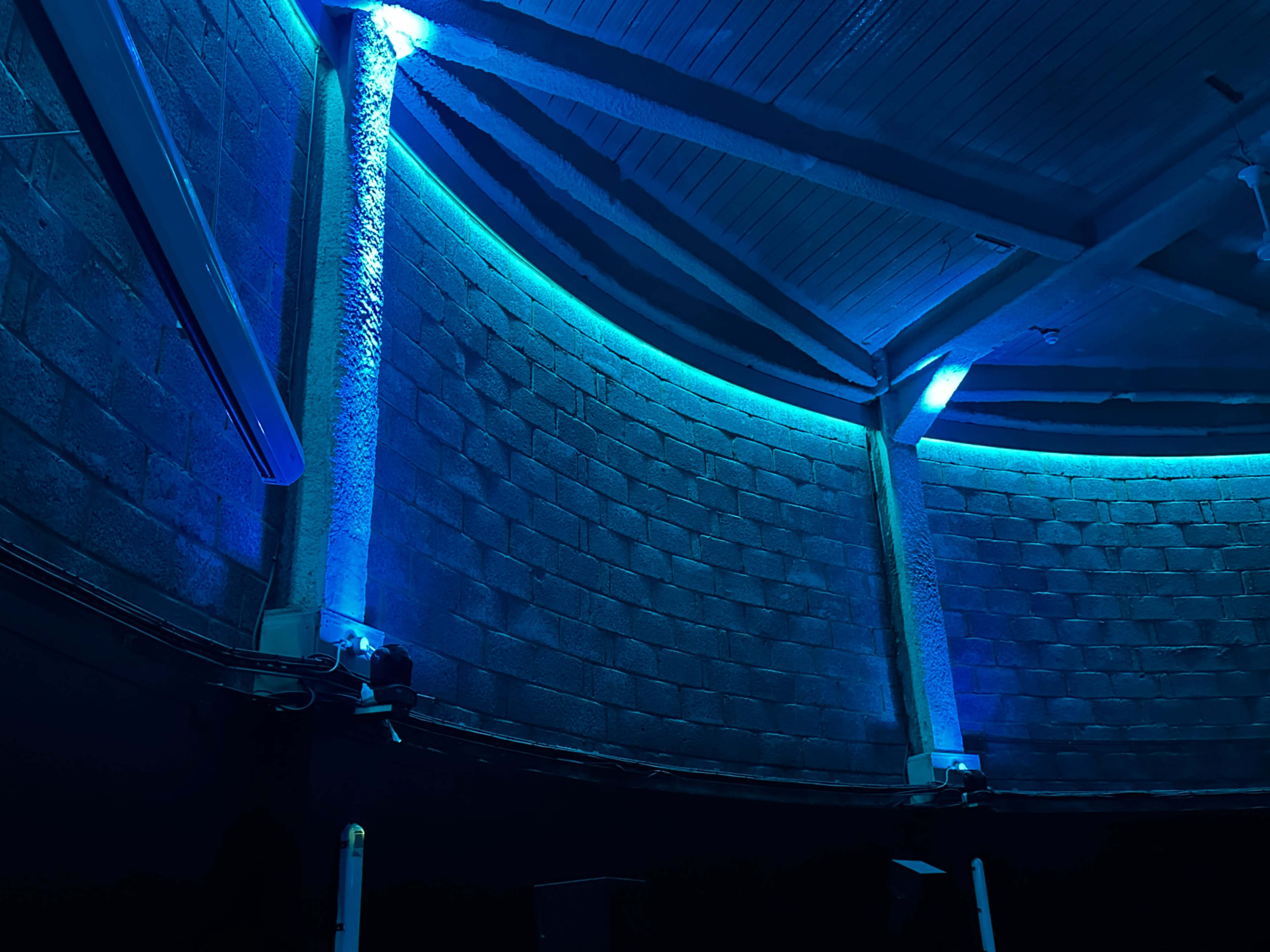 The image shows a curved wall interior illuminated by blue LED lights in a dimly lit space.