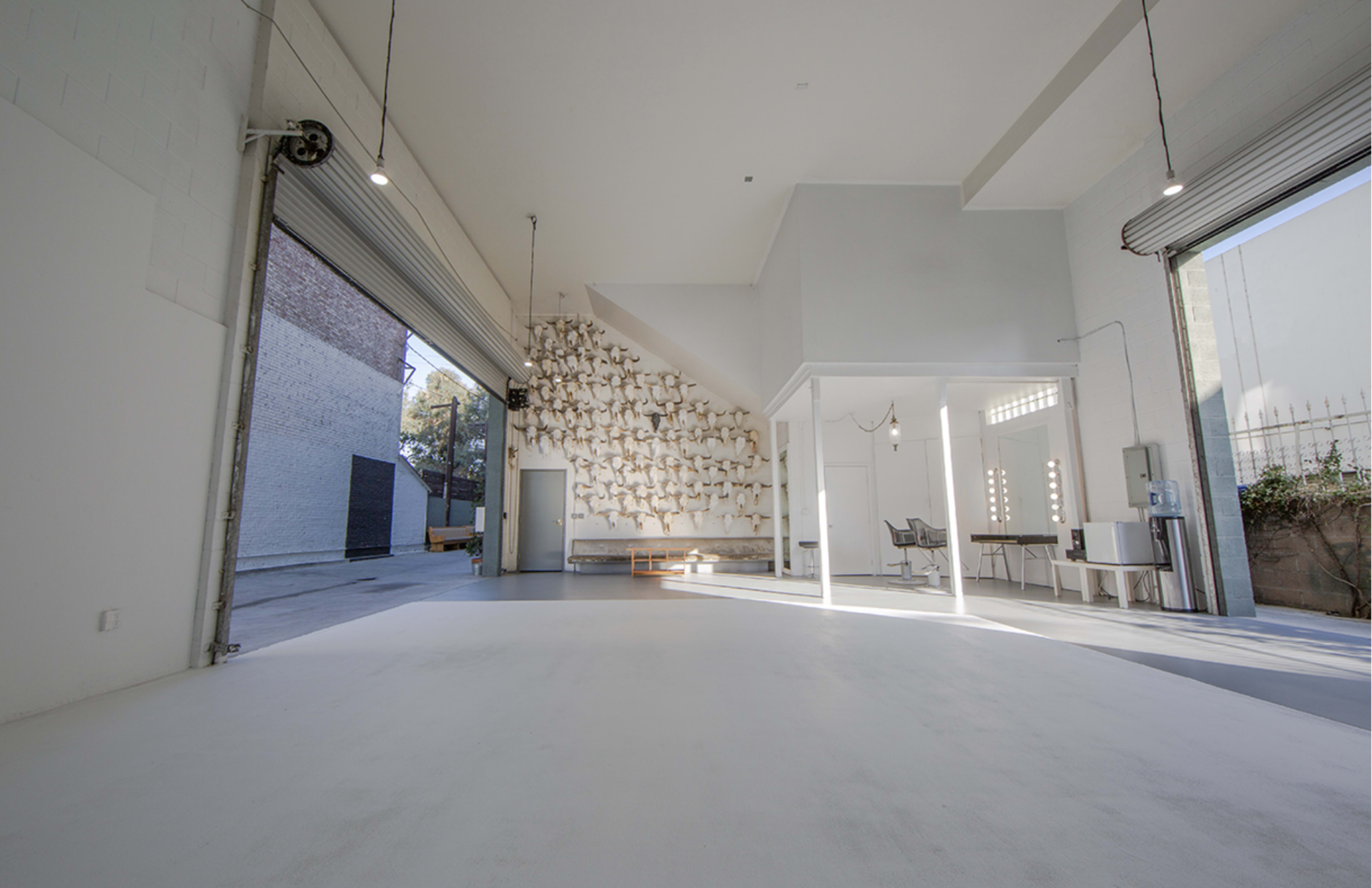 A spacious, modern interior with large windows, white walls, and a textured wall feature made of tiles or panels.