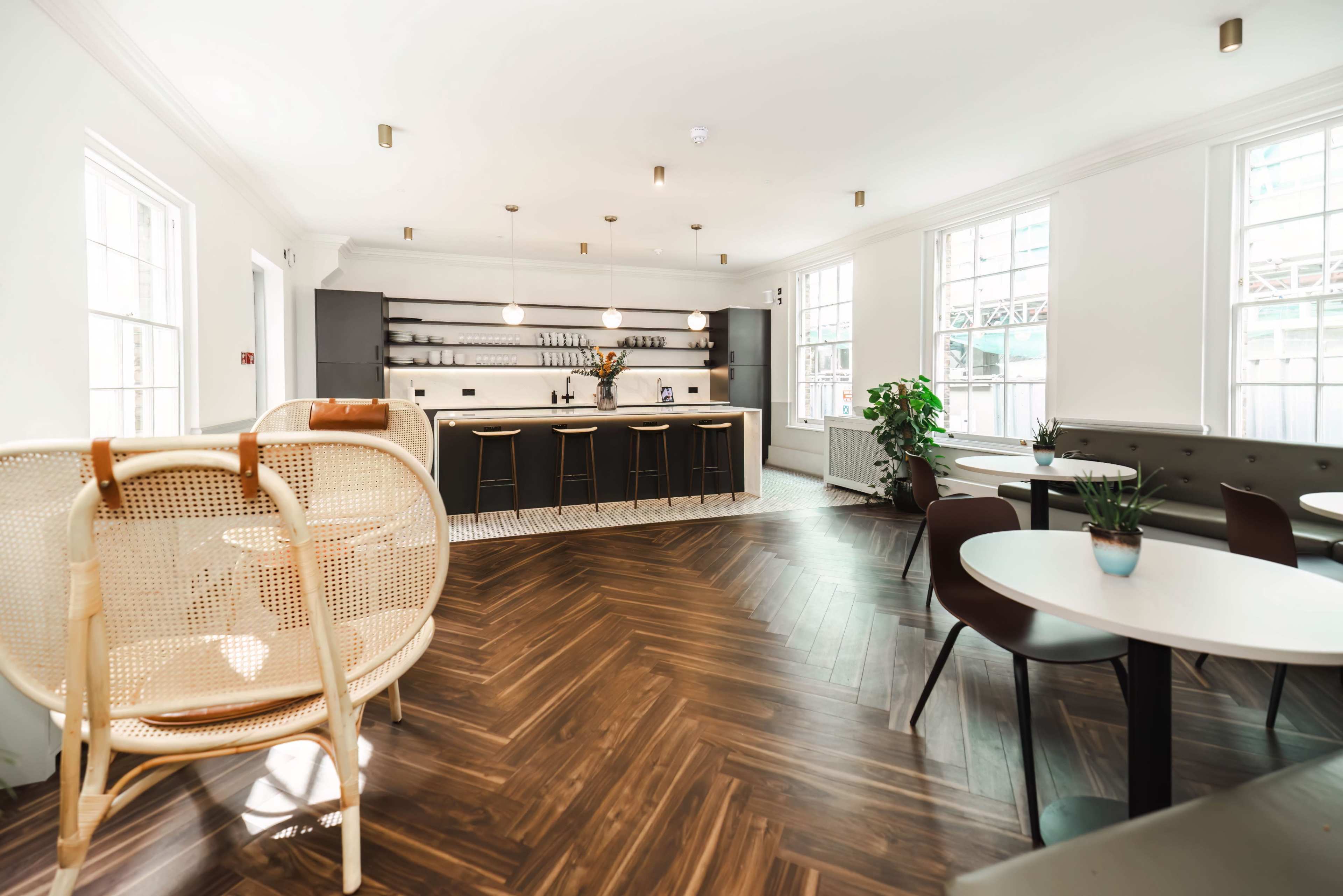 A modern café interior featuring a bar with seating, stylish decor, and large windows allowing natural light to enter.