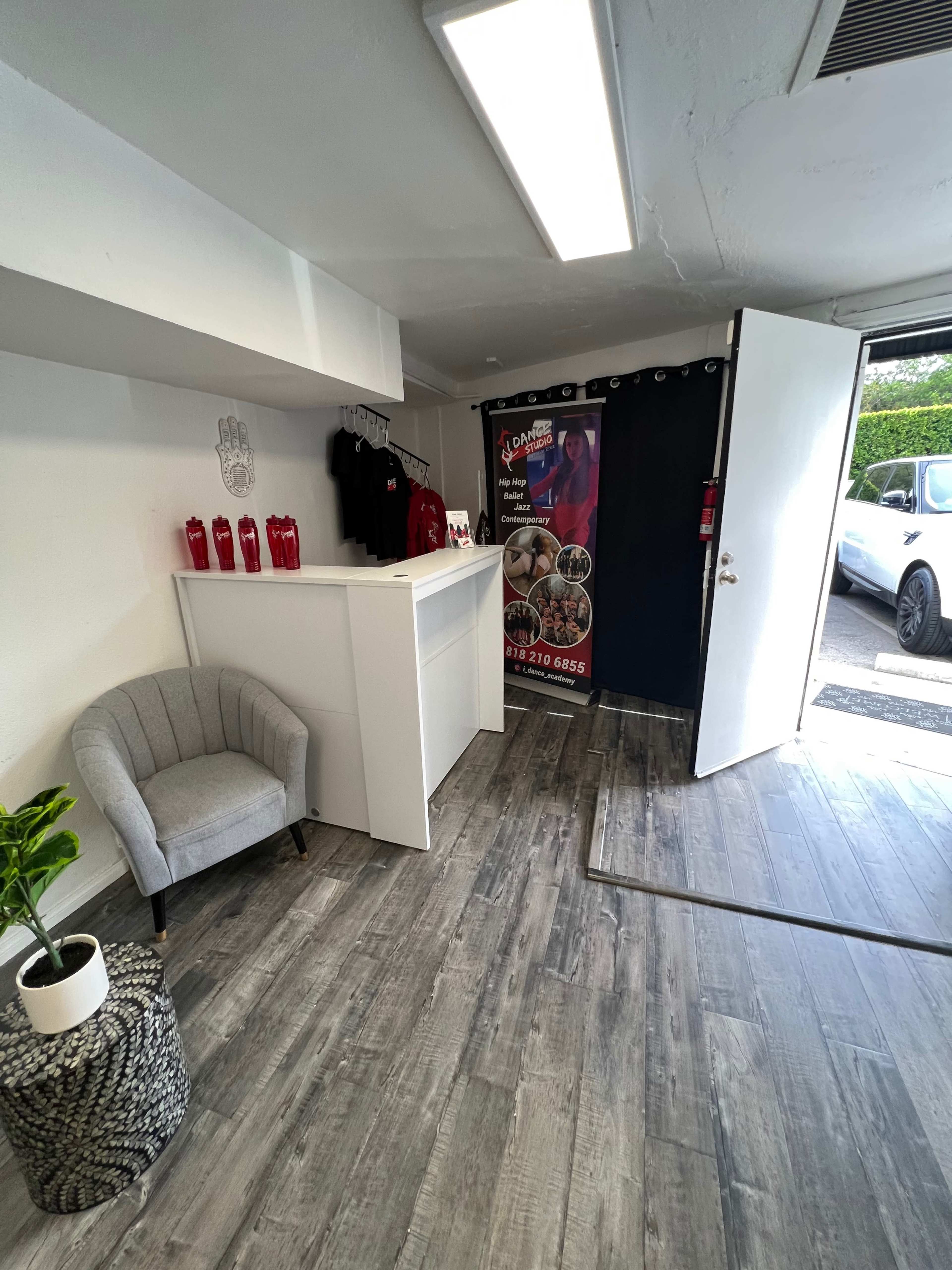 A small retail space with a reception desk, a chair, promotional banners, and an open door leading outside.