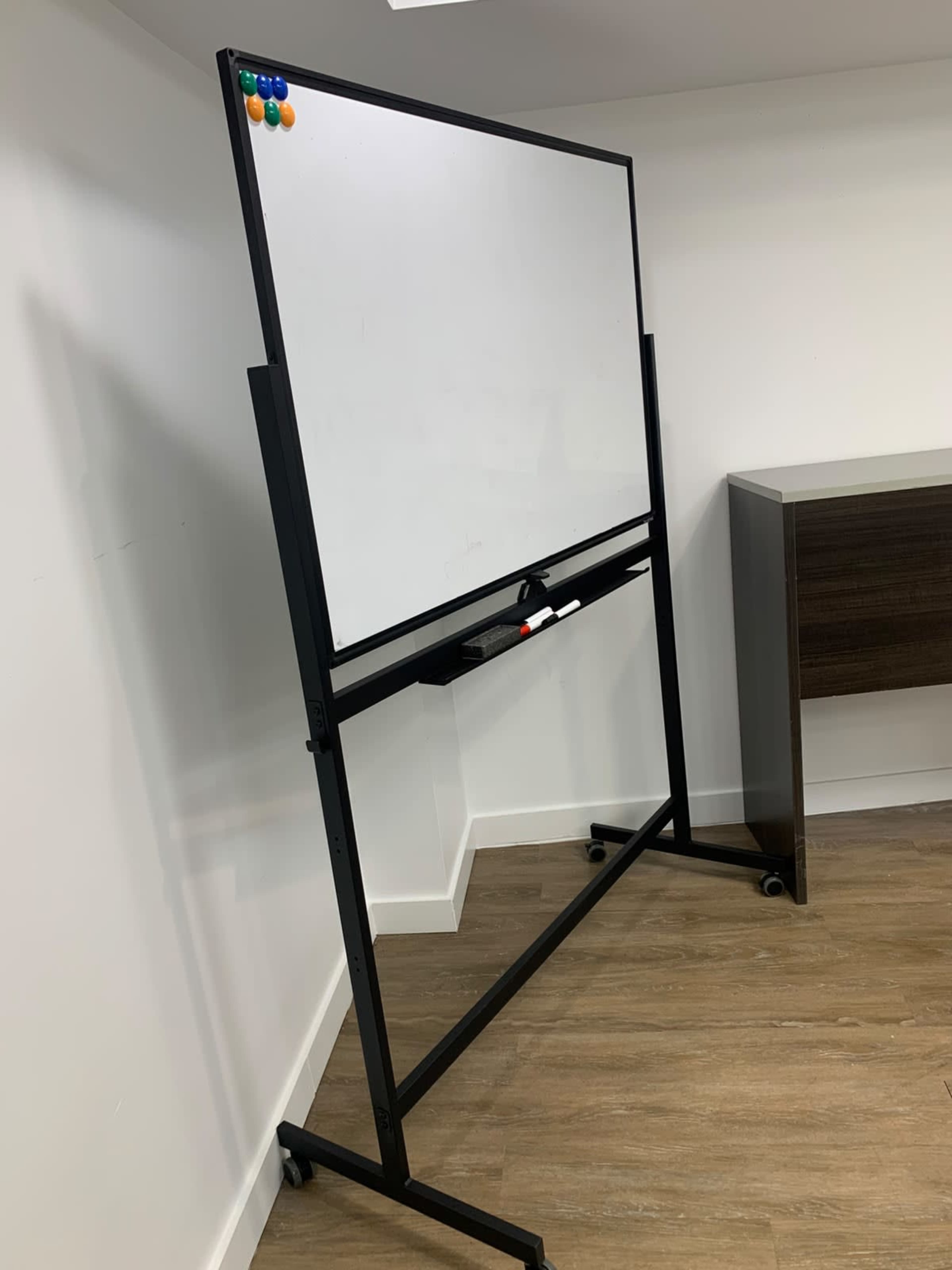 A large, movable whiteboard is positioned against a wall in an office space.