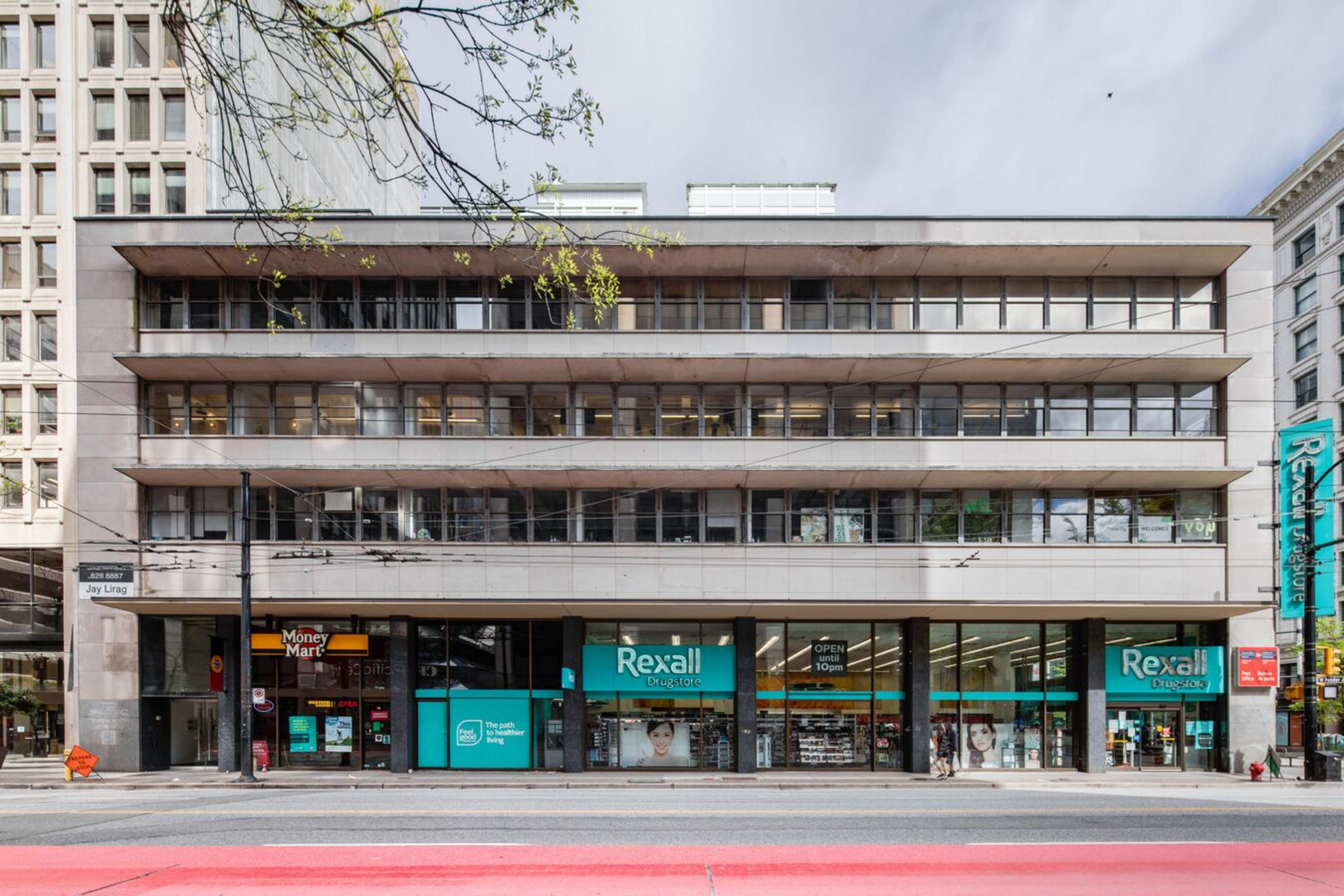 A four-story commercial building featuring large windows and a storefront for Rexall at street level.