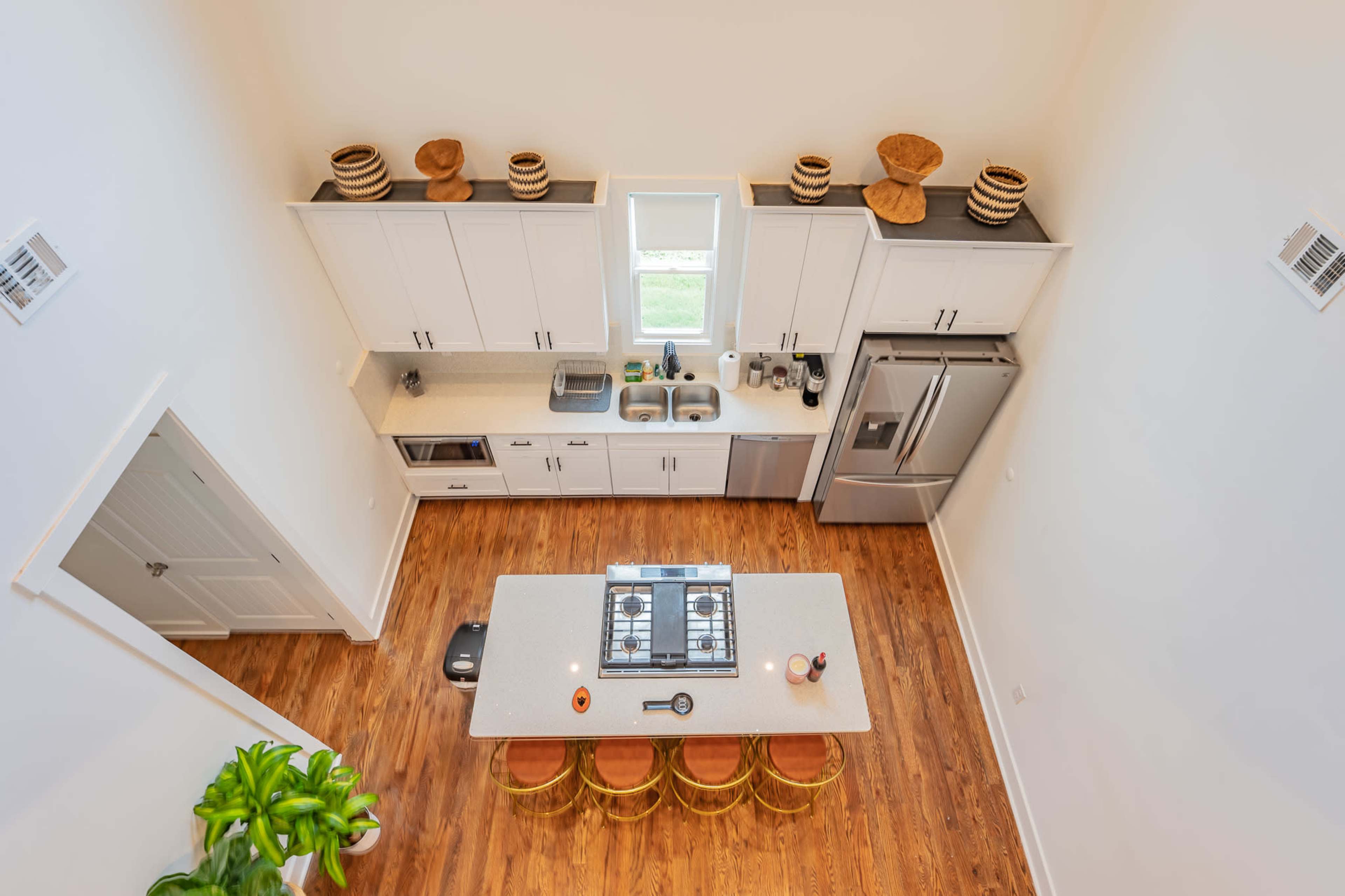 A modern kitchen with a central island, stainless steel appliances, and wooden flooring.