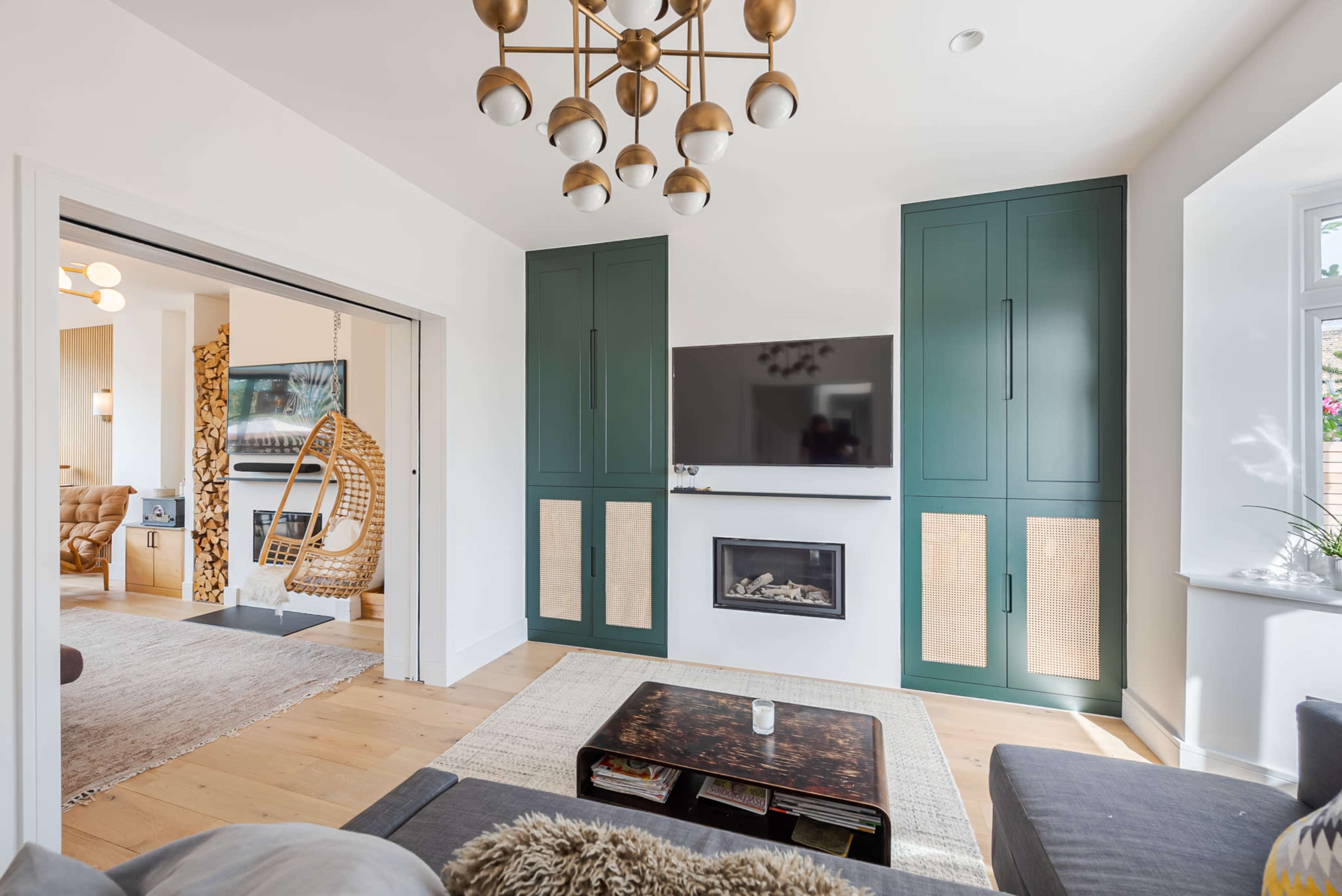 The living room features a modern design with a fireplace below a wall-mounted television and green cabinetry.