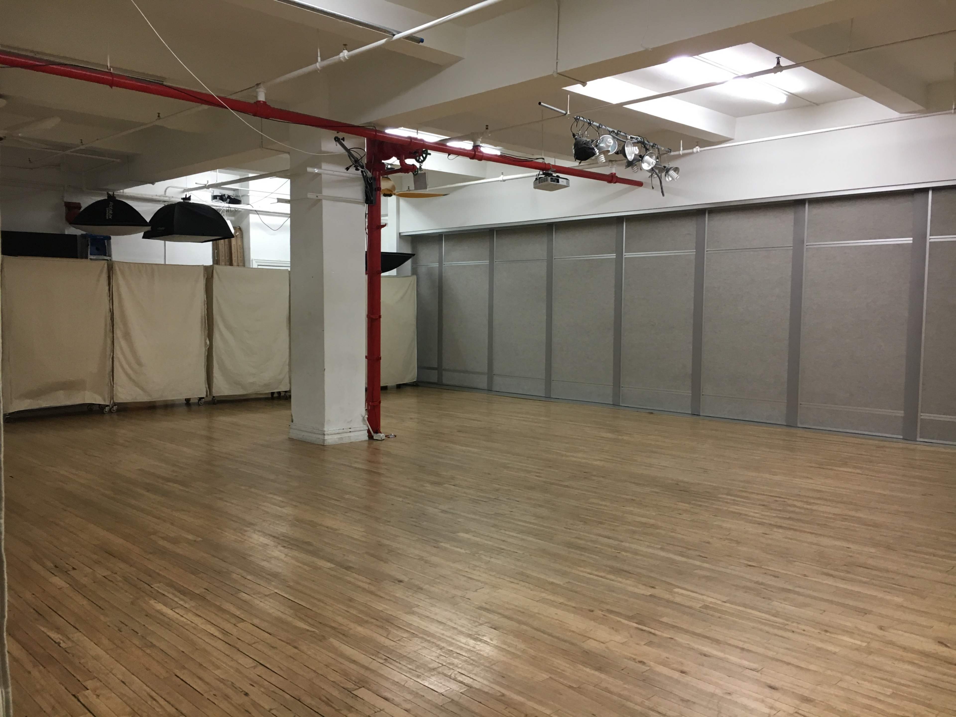 The image shows a spacious, empty room with wooden floors, a red pillar, and gray partition walls.