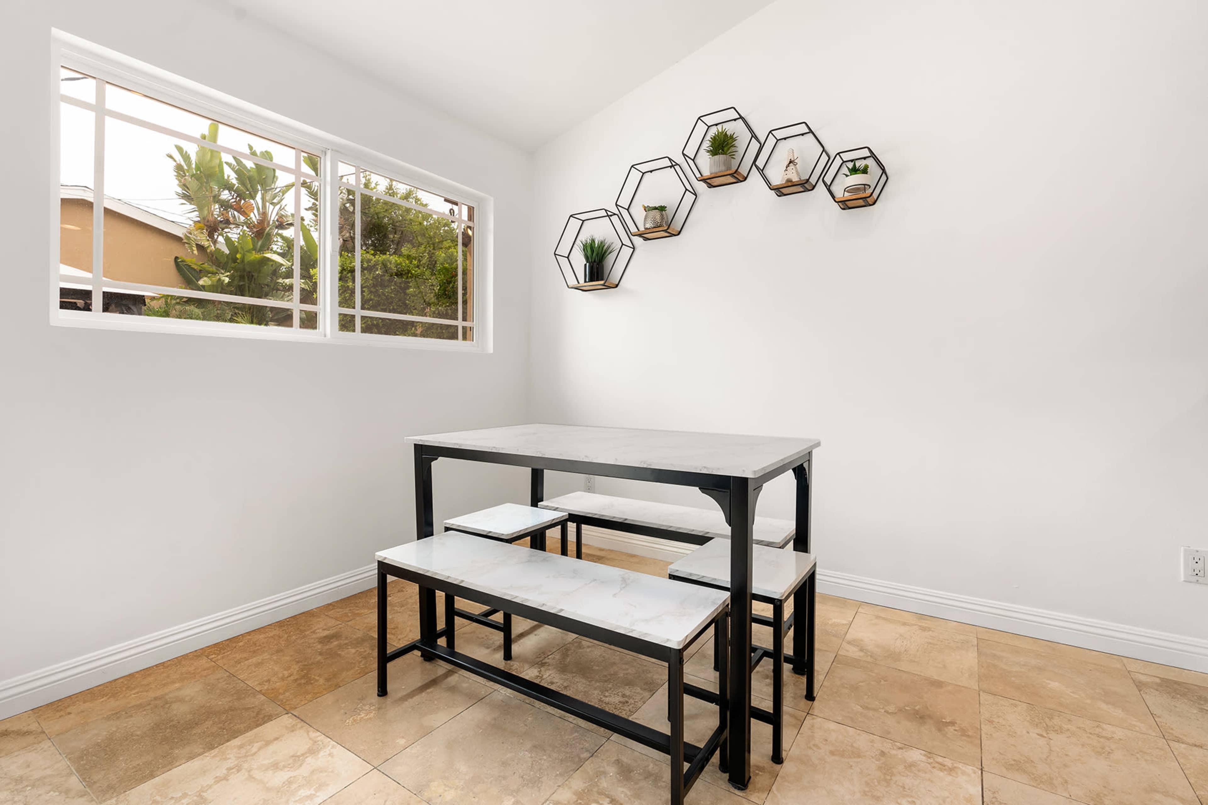 A minimalistic dining area features a rectangular table with benches and geometric wall planters.
