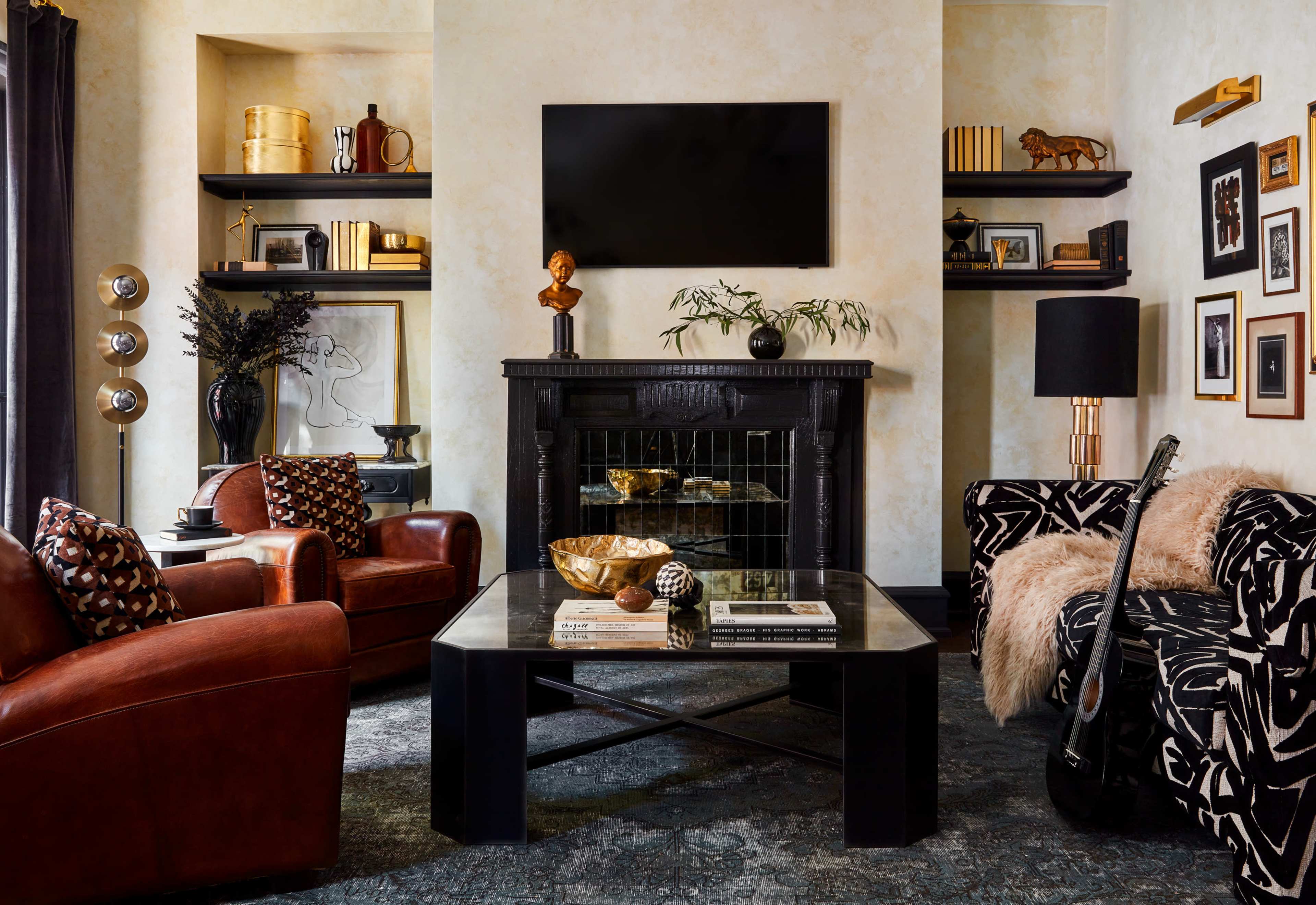 A stylish living room featuring a black fireplace, a television mounted above, and a mix of leather and patterned furniture arranged around a coffee table.