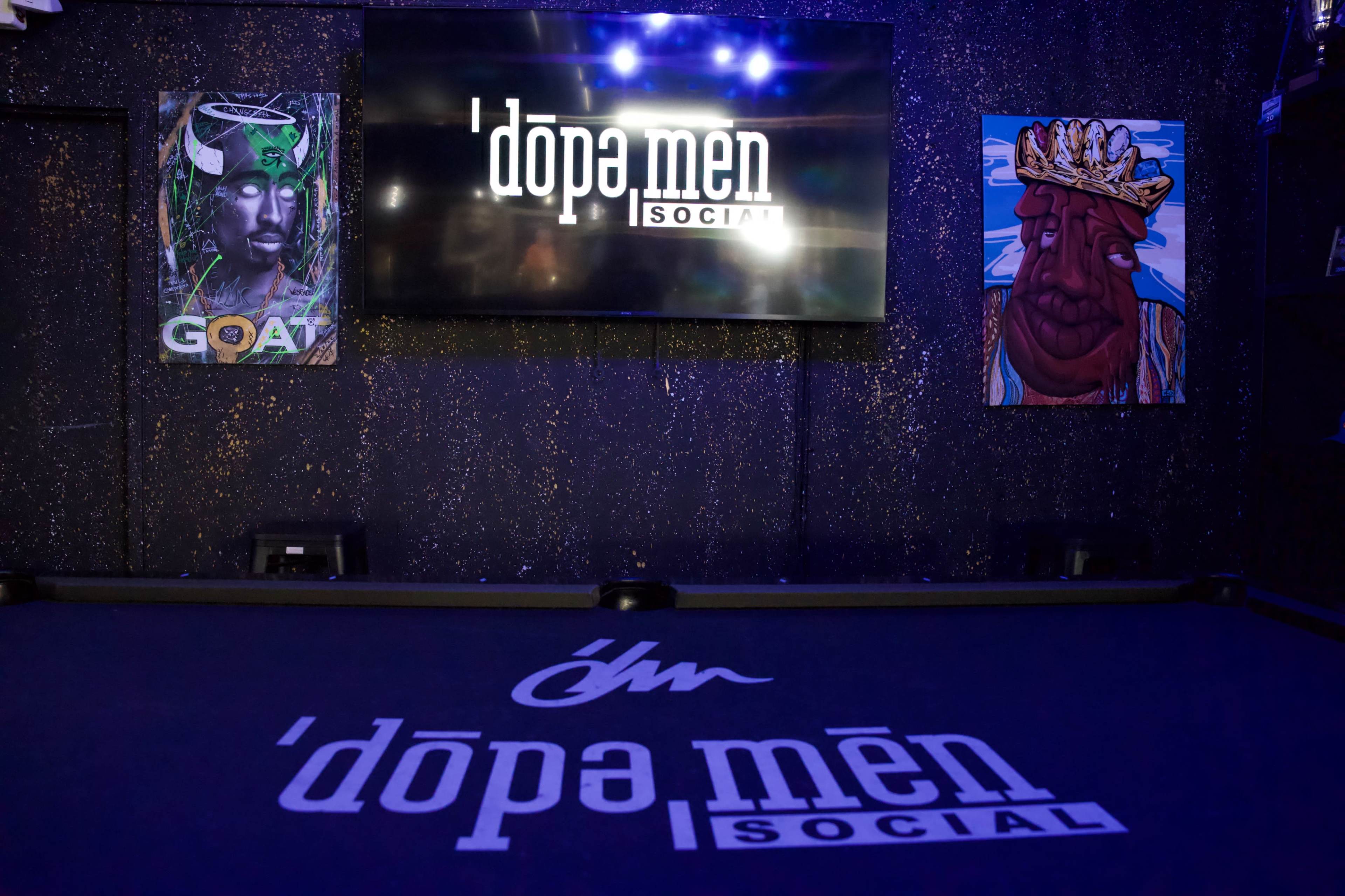 The image shows an interior of a venue called 'dopa men SOCIAL', featuring a large screen and vibrant wall art.