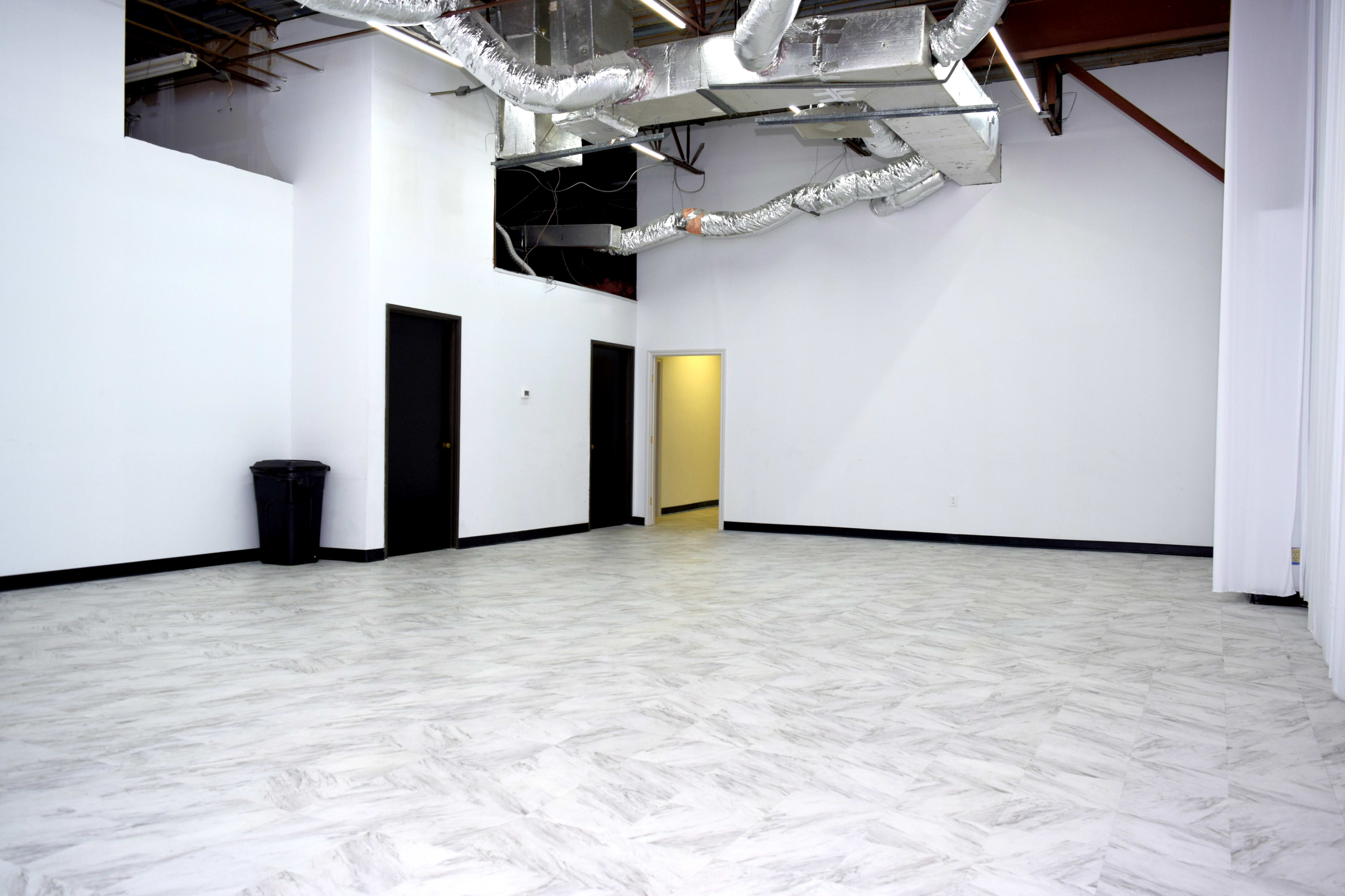 The image shows an empty room with a marble-patterned floor, white walls, and two doors, one of which is slightly open, revealing a yellow-lit space beyond.