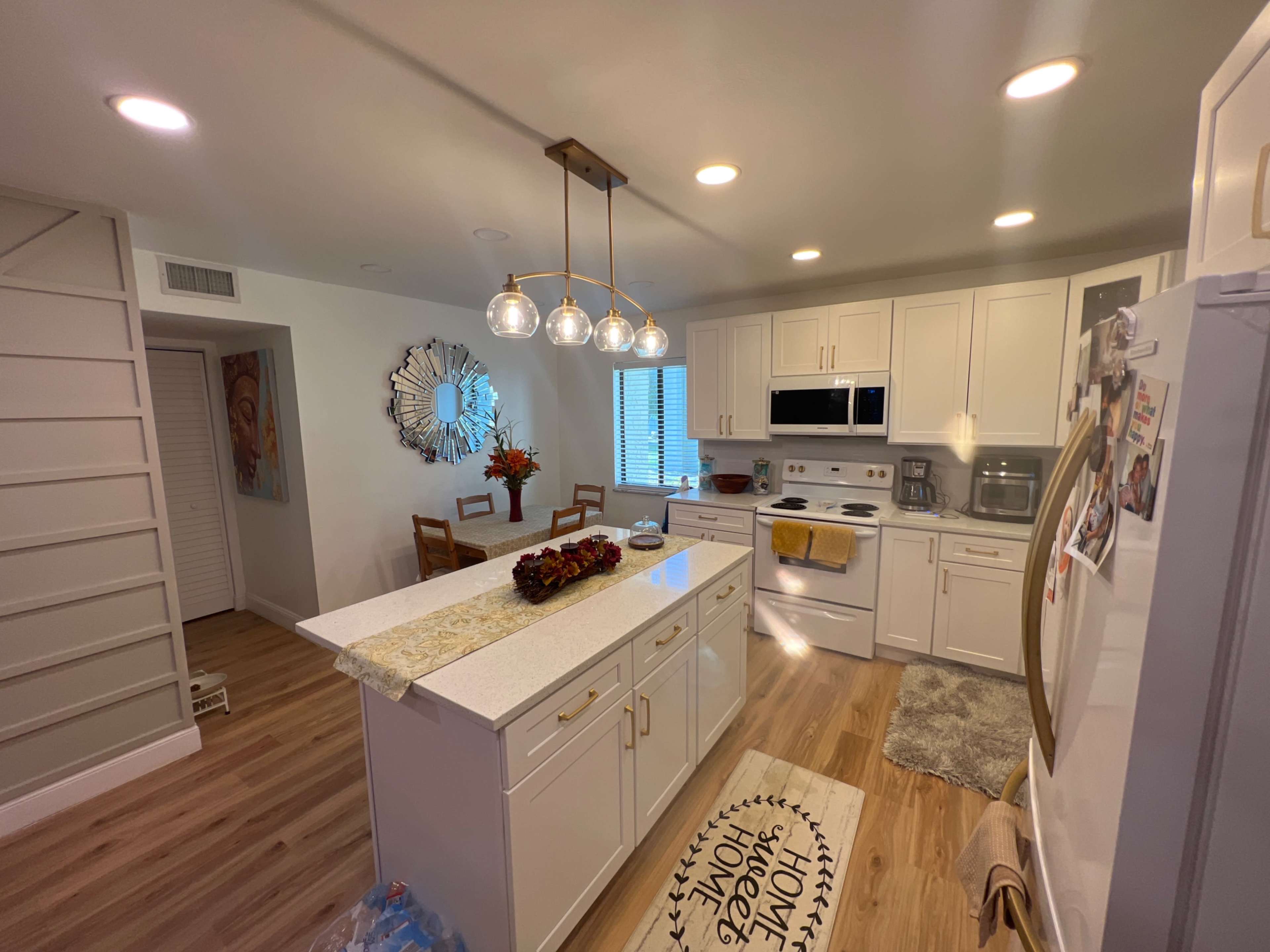 The image shows a modern kitchen featuring white cabinetry, stainless steel appliances, and a decorative rug on the floor.