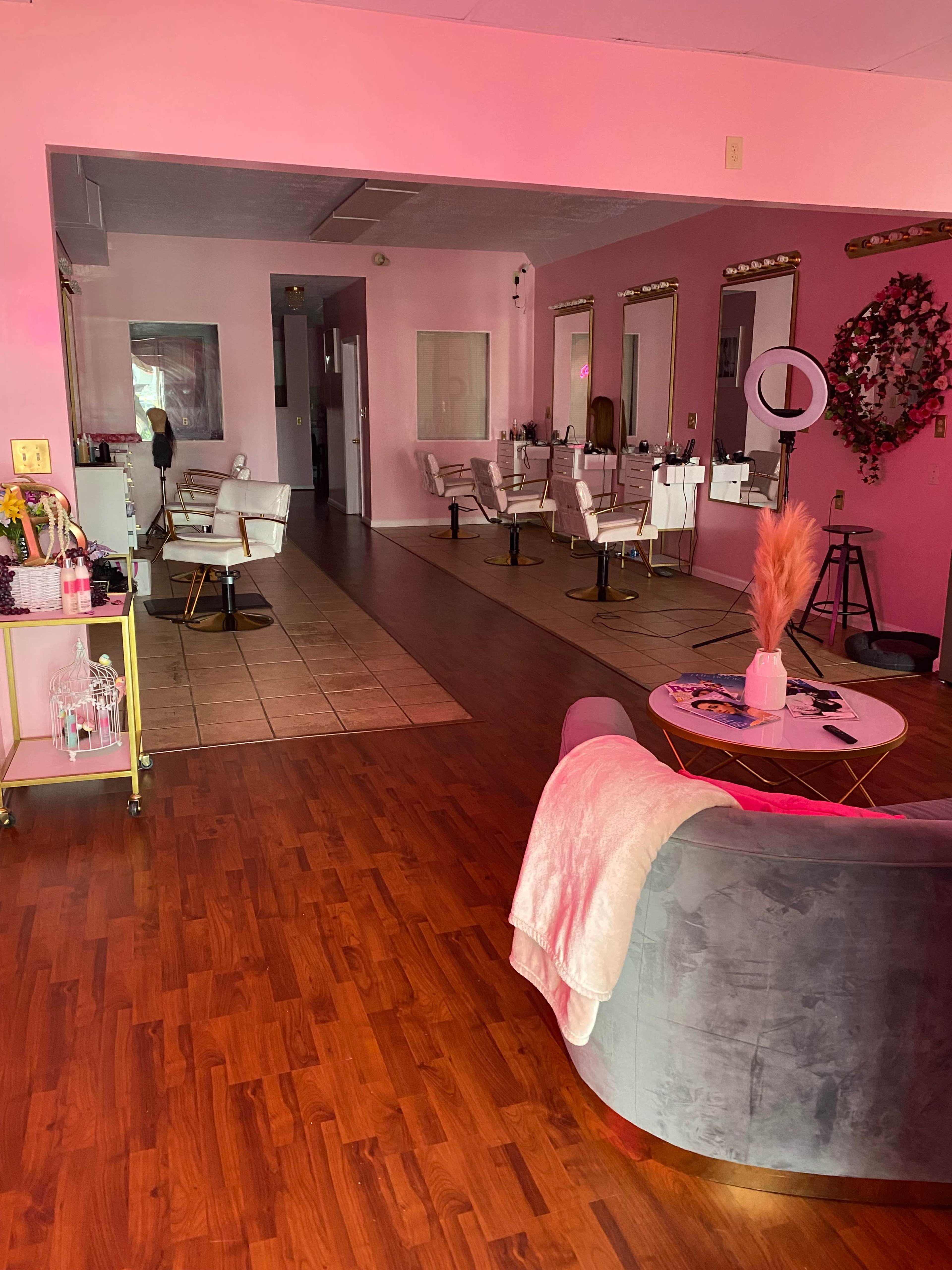 The interior of a salon featuring multiple styling chairs, mirrors, and a cozy seating area with a coffee table.