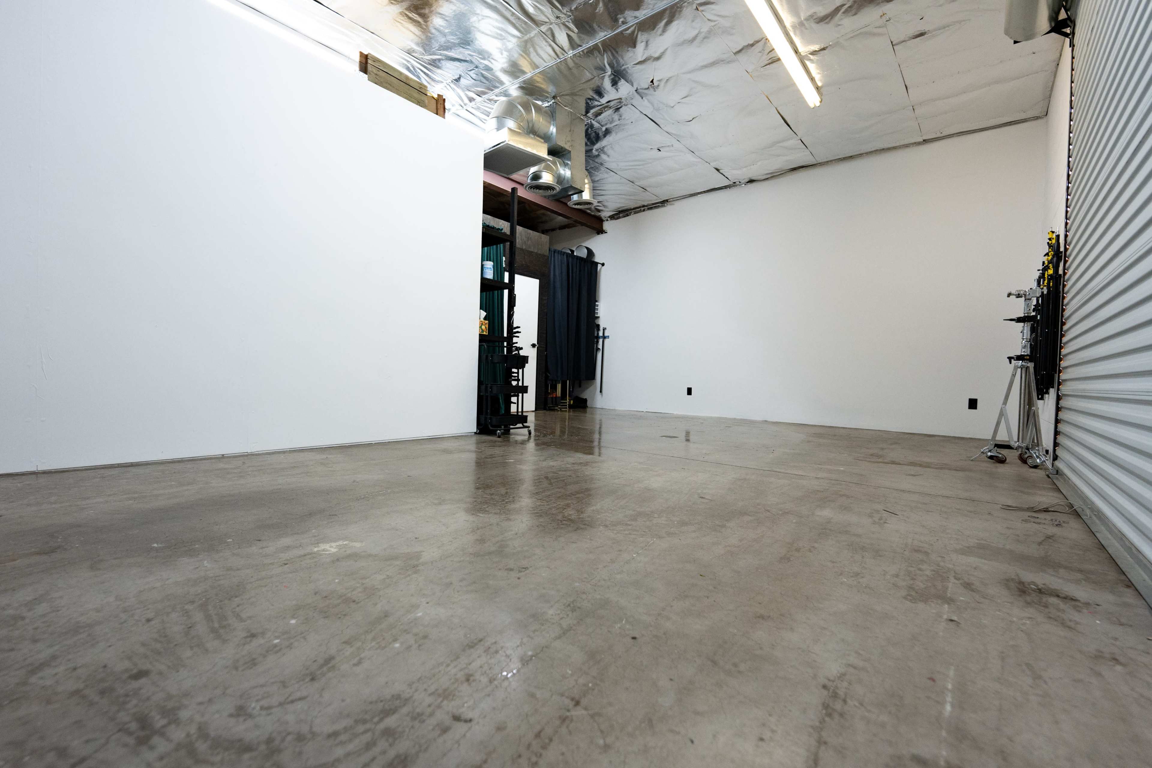 An empty room with concrete flooring, white walls, and industrial lighting.