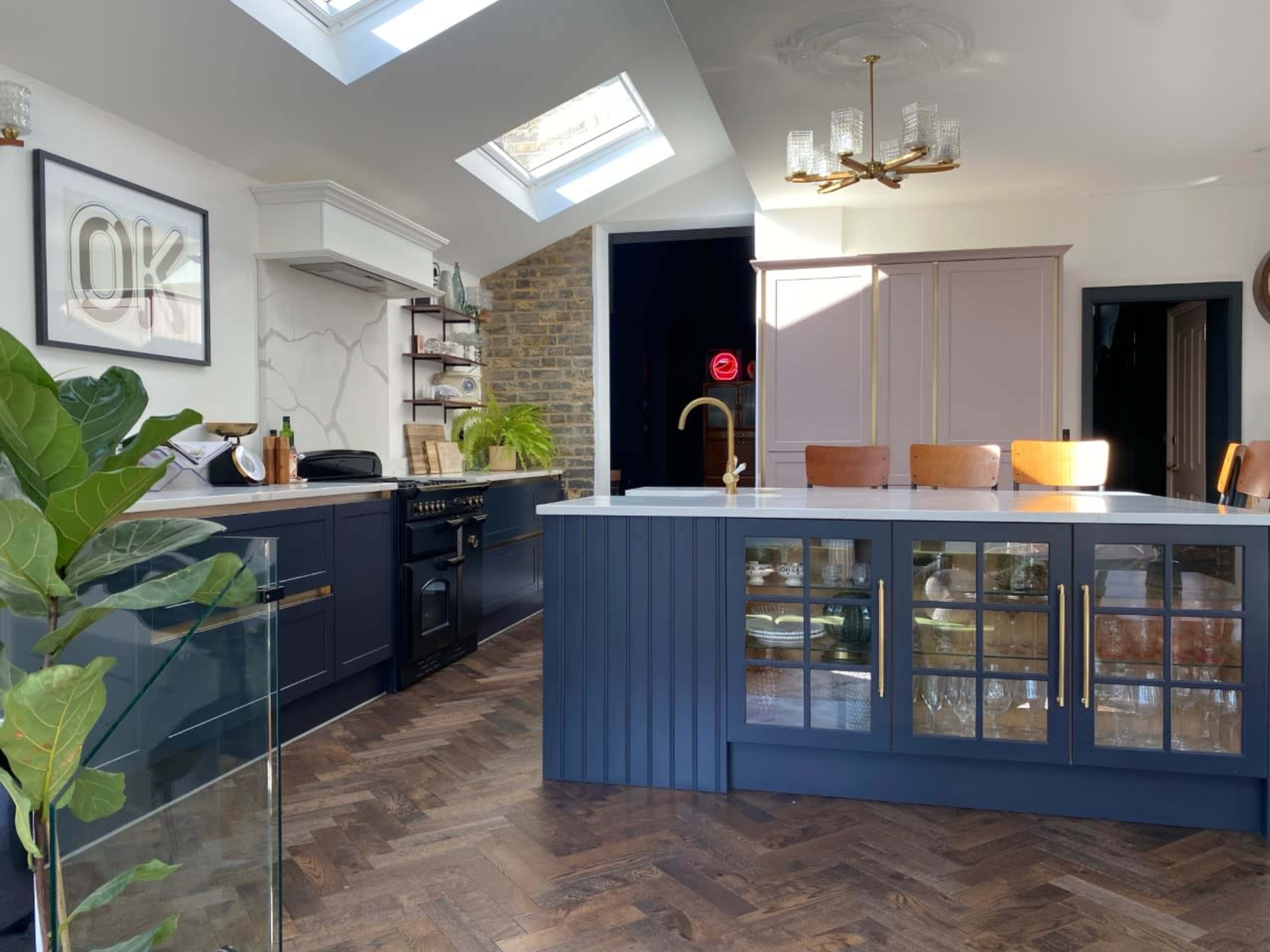 The kitchen features modern cabinetry, a central island with bar seating, and natural light streaming in through skylights.