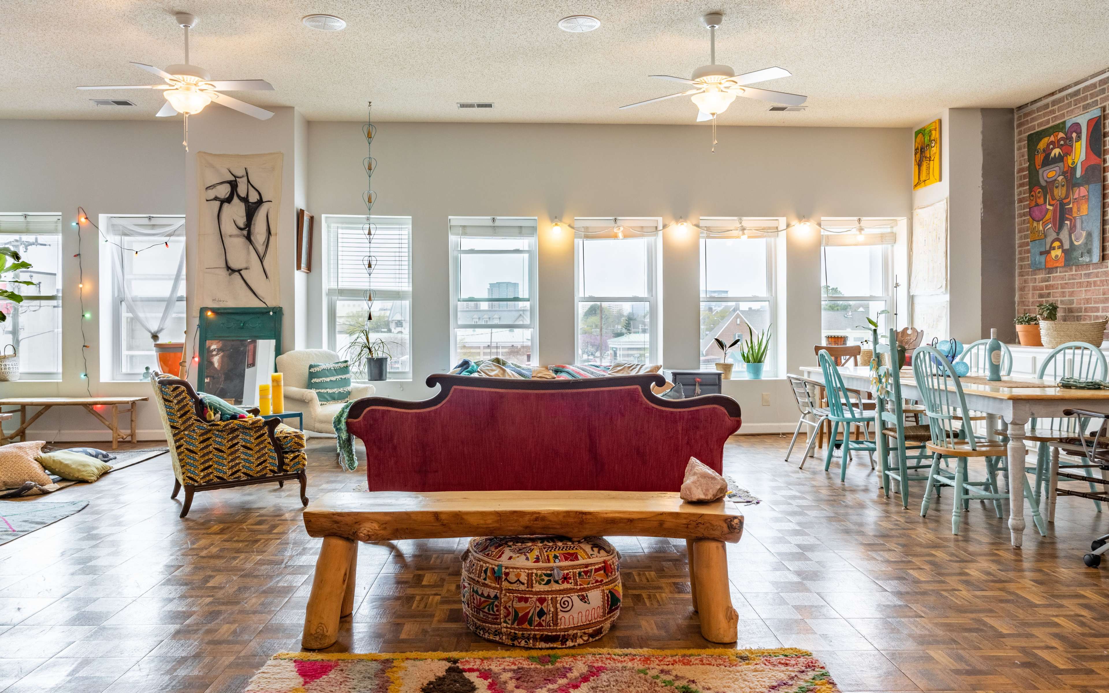 A bright, open living space with a mix of colorful furniture, large windows, and an inviting dining area.
