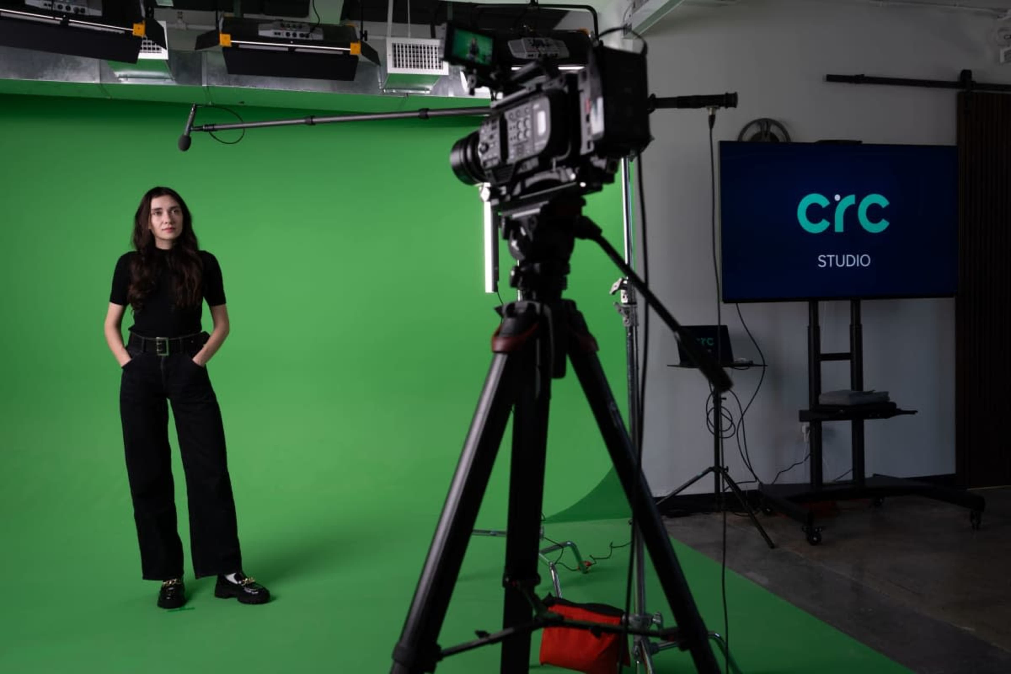 A person stands in front of a green screen while a camera is positioned on a tripod, and a monitor displays the text "CIRC STUDIO."