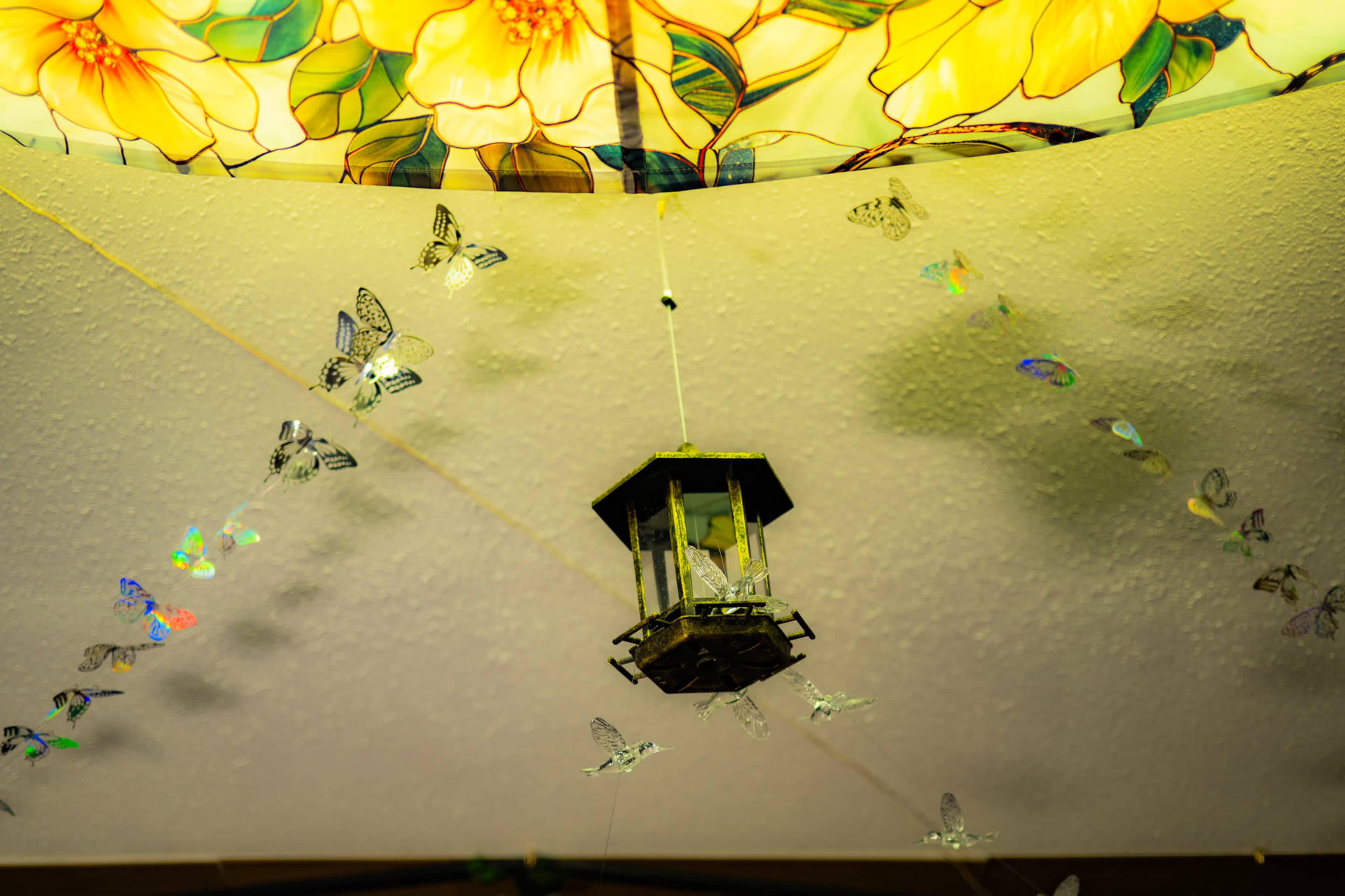 A decorative lantern hangs from the ceiling, surrounded by shimmering butterfly ornaments and a floral lampshade.