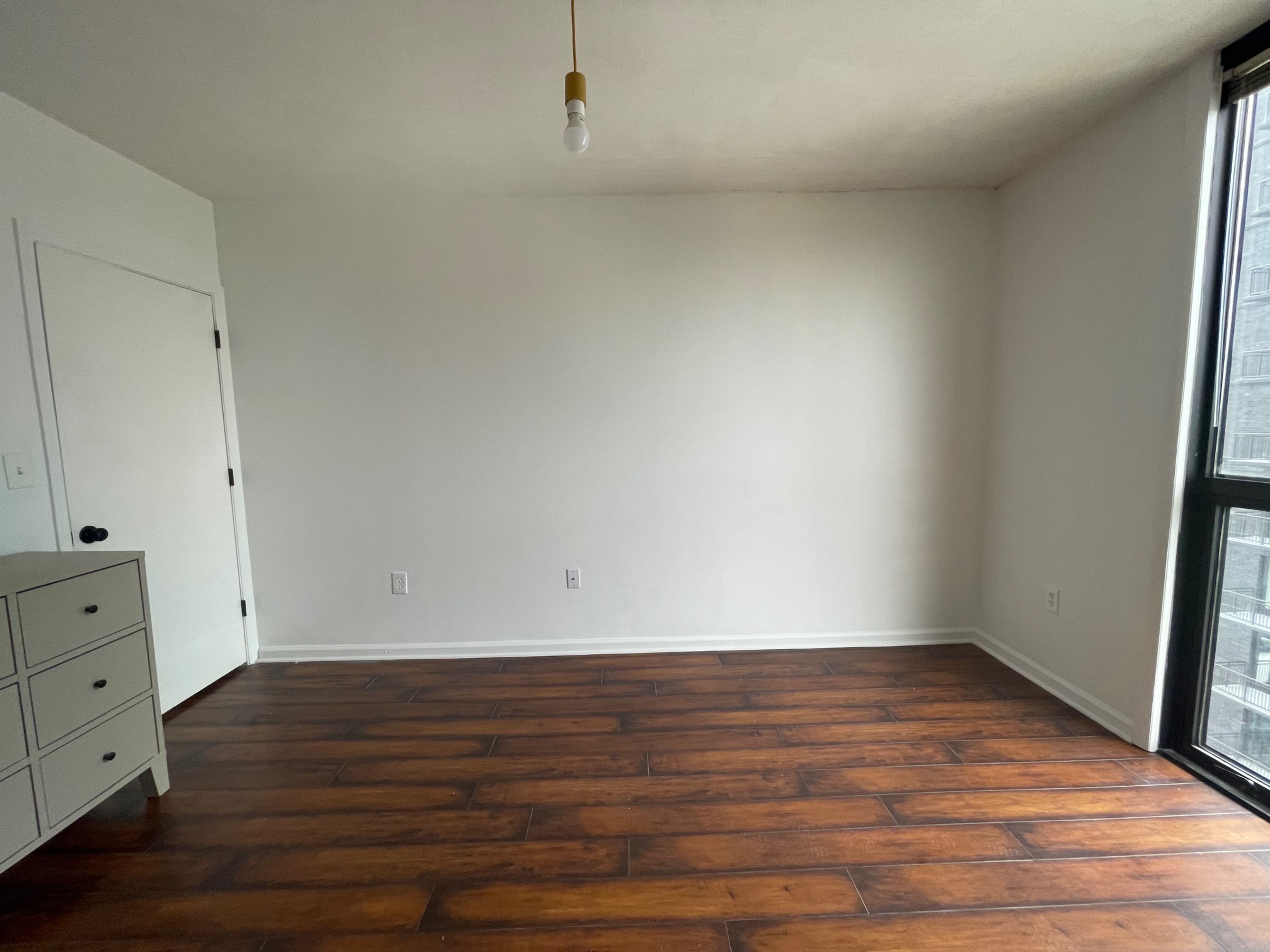 The room features hardwood flooring, one light fixture, and a single door leading to the outside.