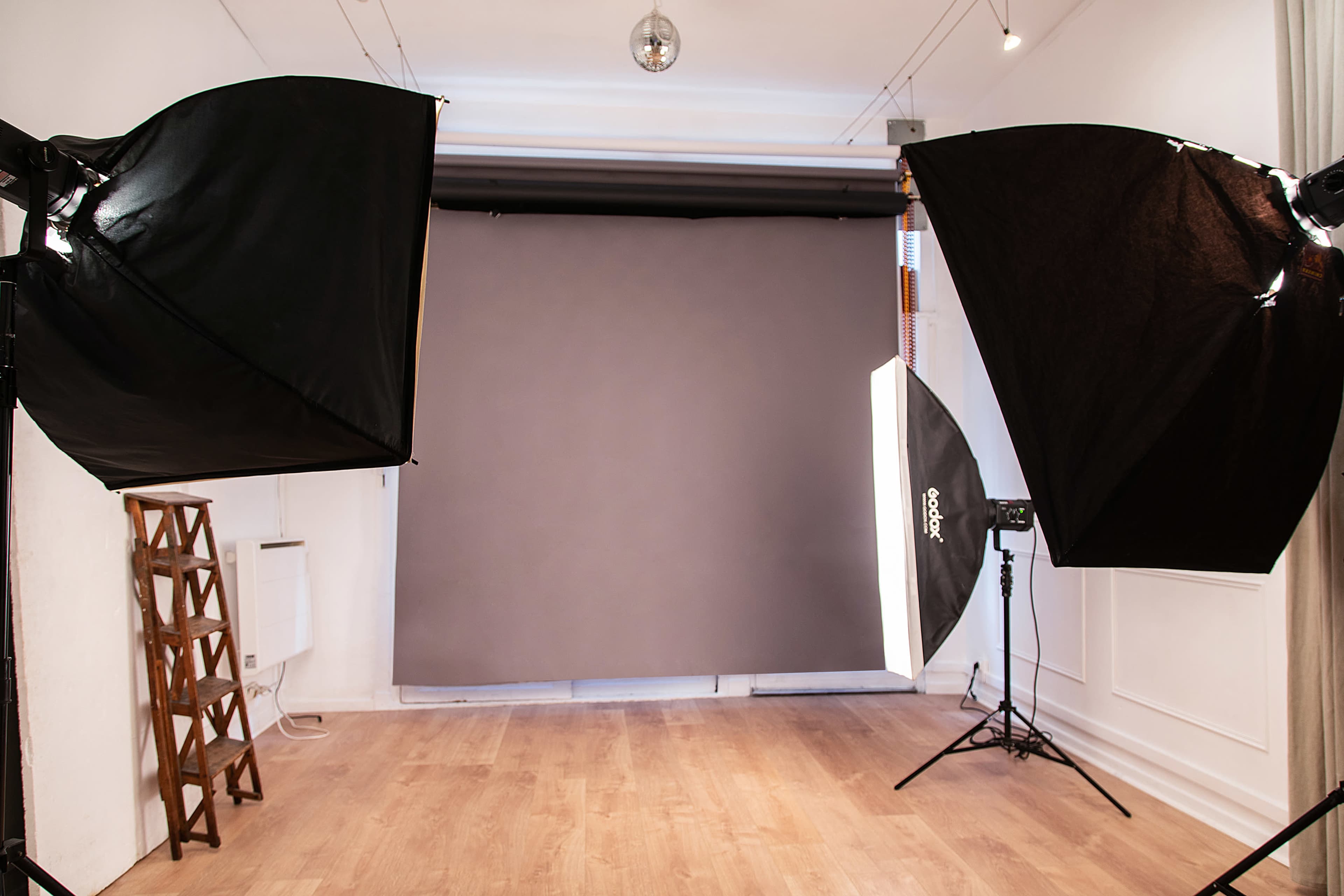 A photography studio with two large softbox lights positioned on either side of a neutral gray backdrop.