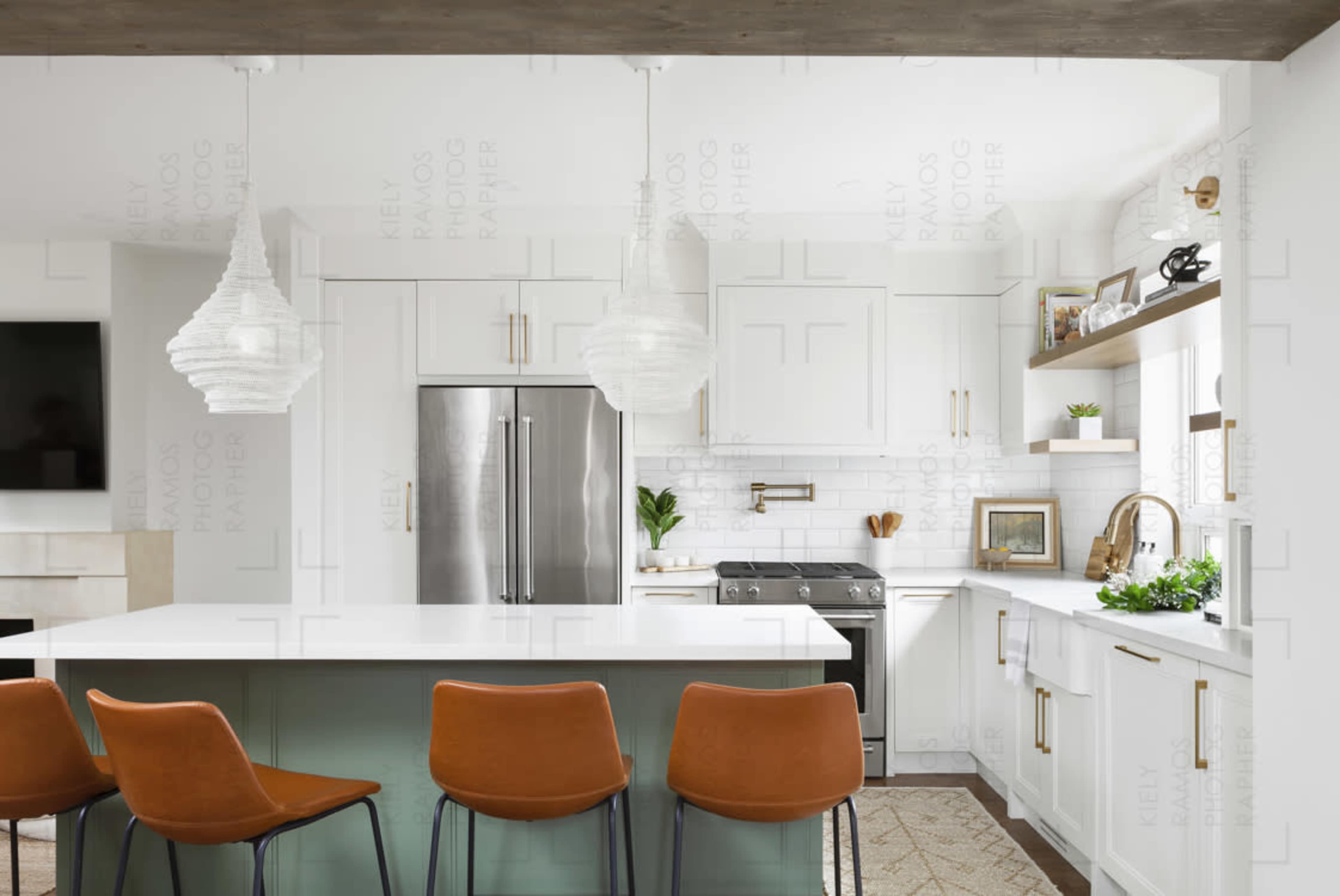 A modern kitchen features white cabinetry, stainless steel appliances, and a central island with four orange bar stools.