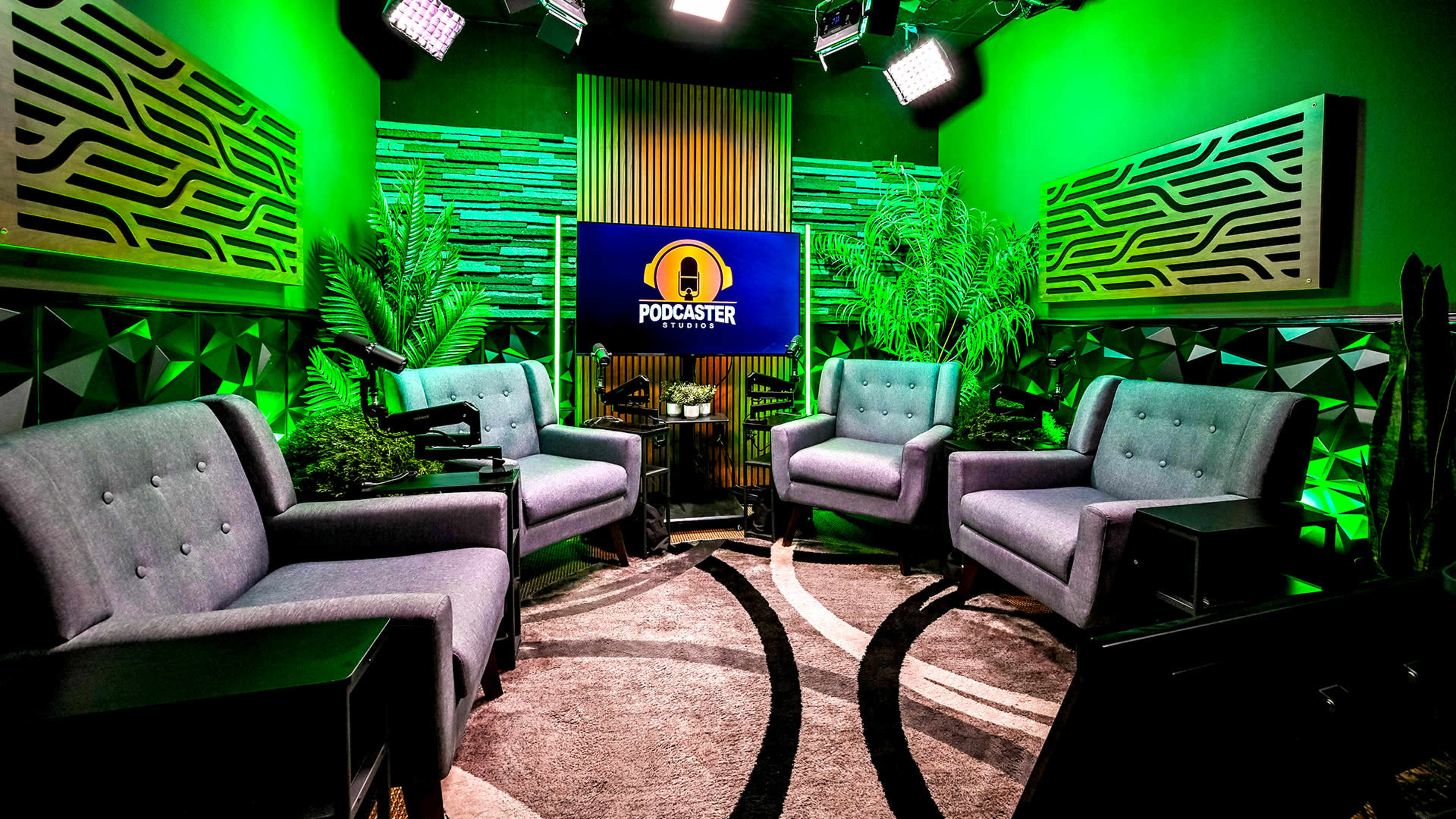 The image features a podcasting studio with green lighting, featuring four gray armchairs arranged around a circular rug, surrounded by plants and decorative wall panels.