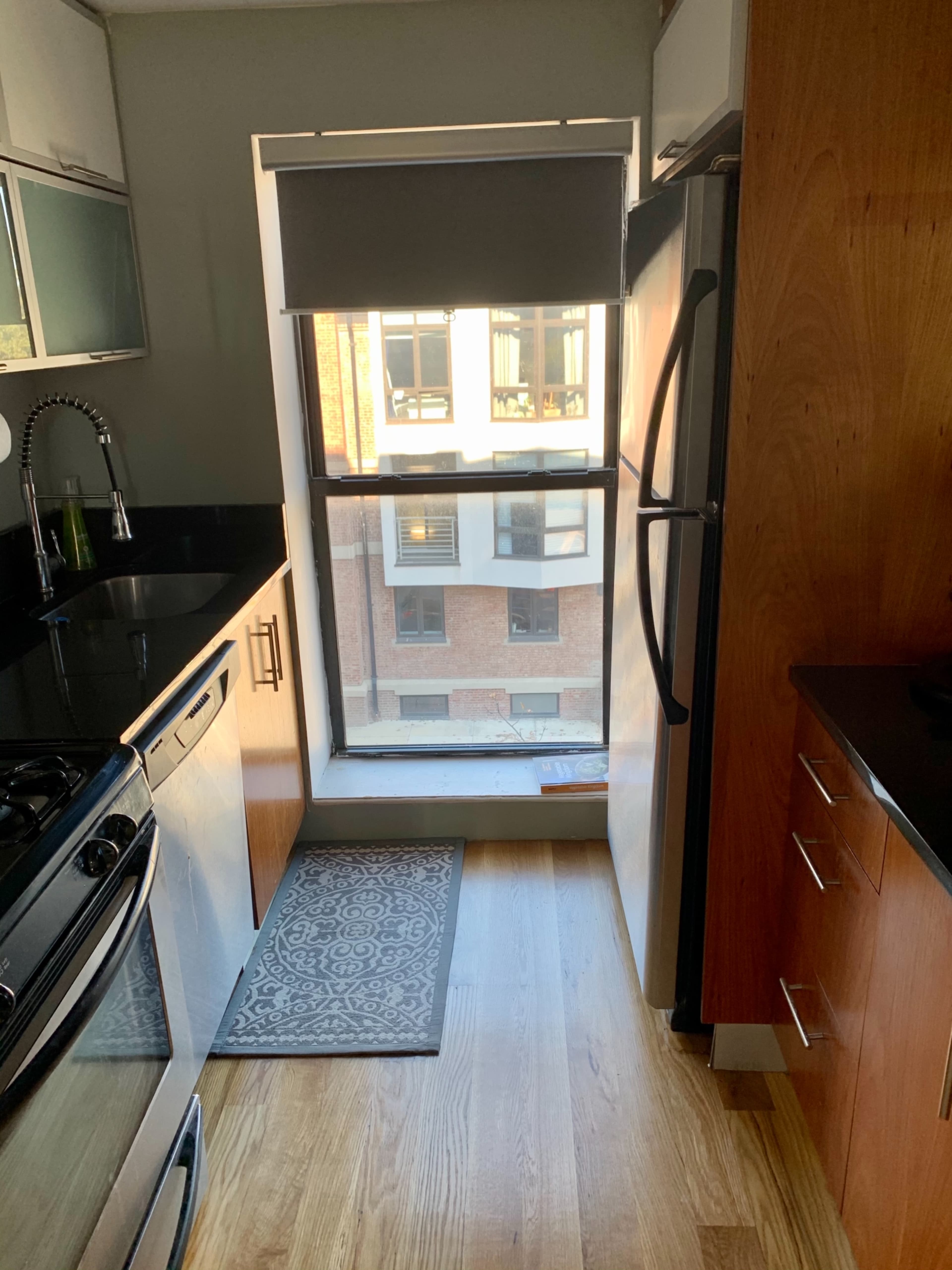 A modern kitchen with stainless steel appliances, a window allowing natural light, and wooden cabinetry.