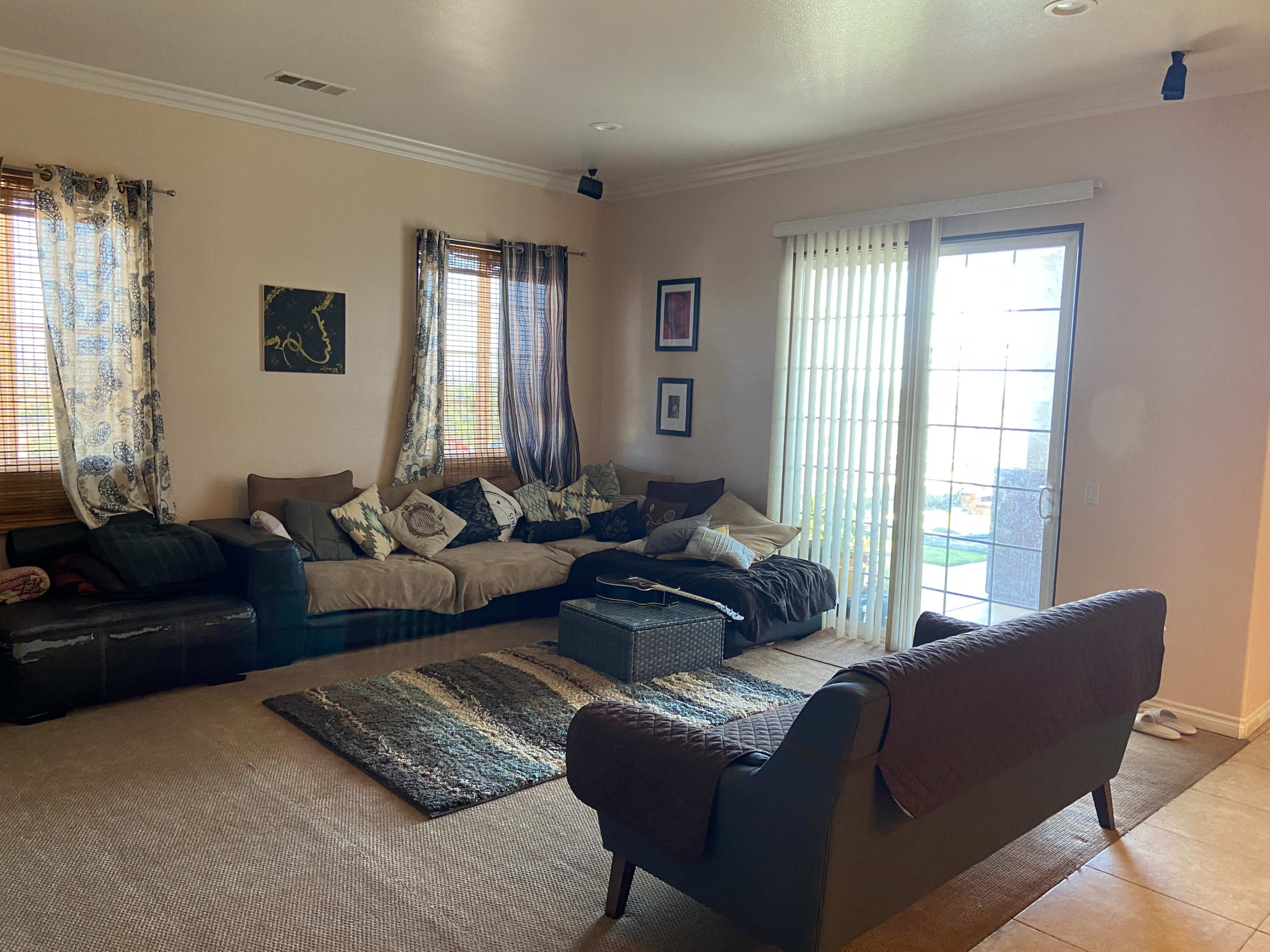 A living room with a large sofa, a coffee table, and sliding glass doors leading to an outdoor area.
