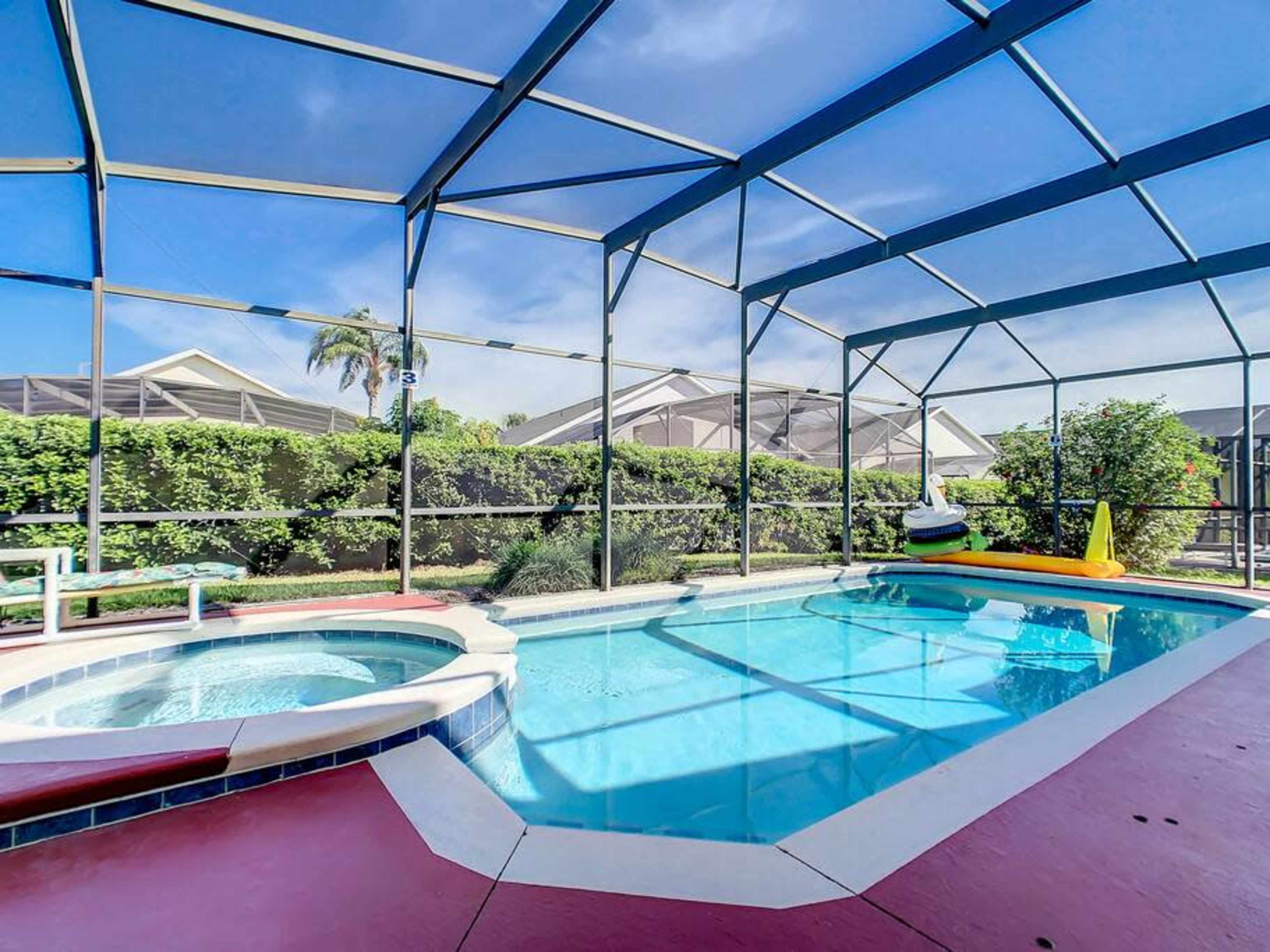 A pool area features a swimming pool, a hot tub, and a slide, all enclosed by a screened canopy.