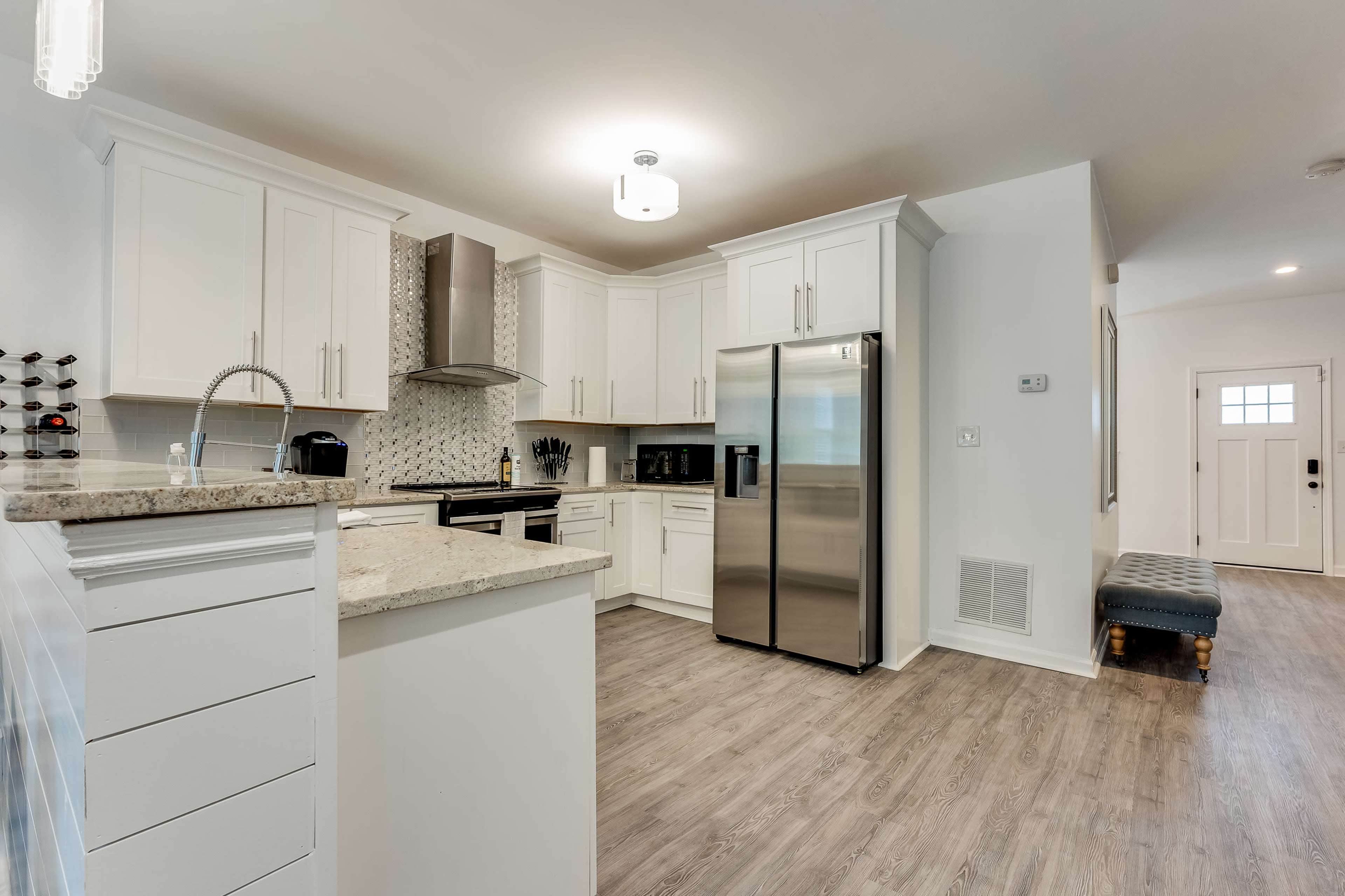 A modern kitchen with white cabinetry, stainless steel appliances, and a granite countertop.