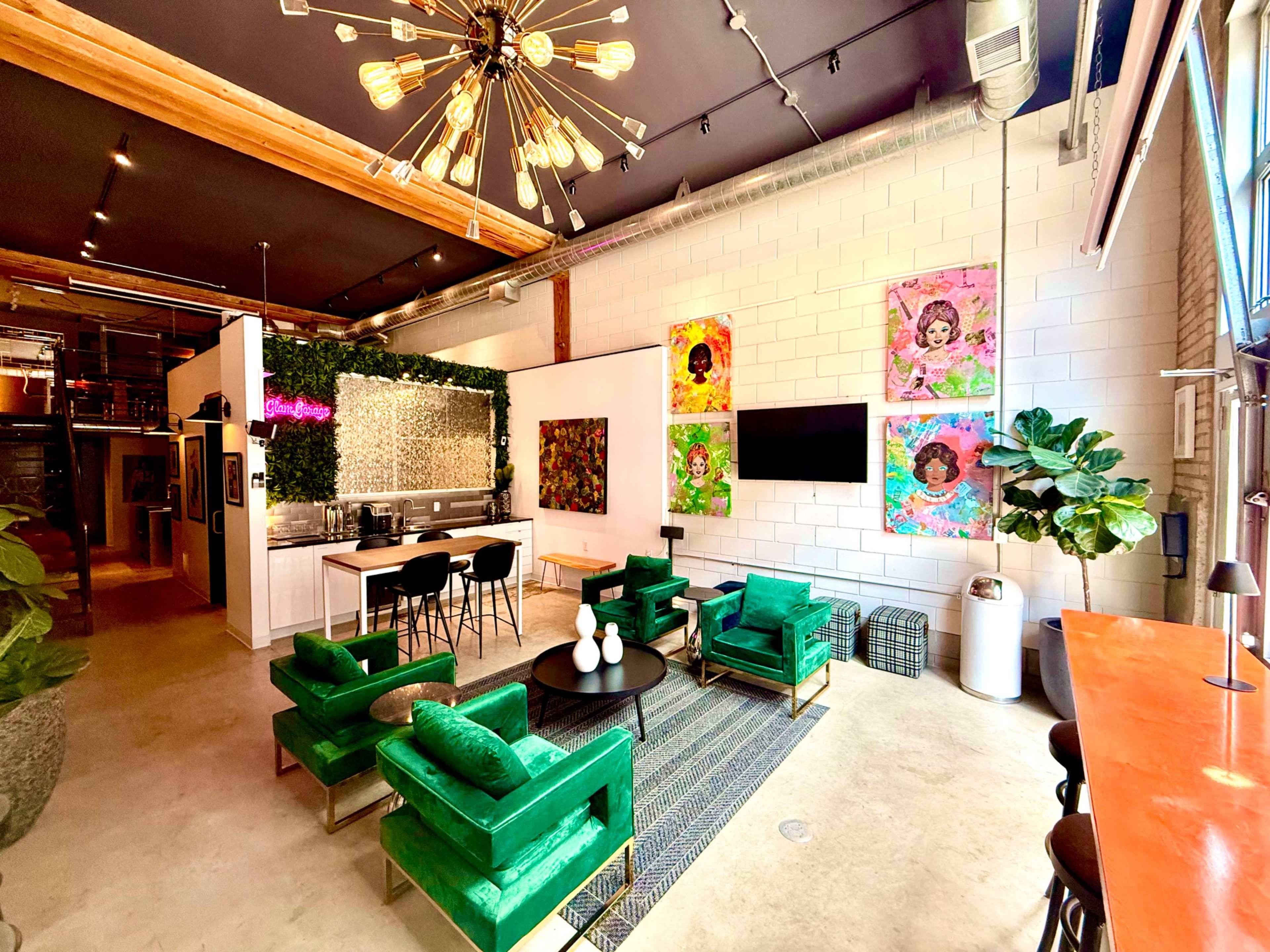 The image shows a modern interior space featuring a green living area with sofas, a bar area, and colorful artwork on the walls.
