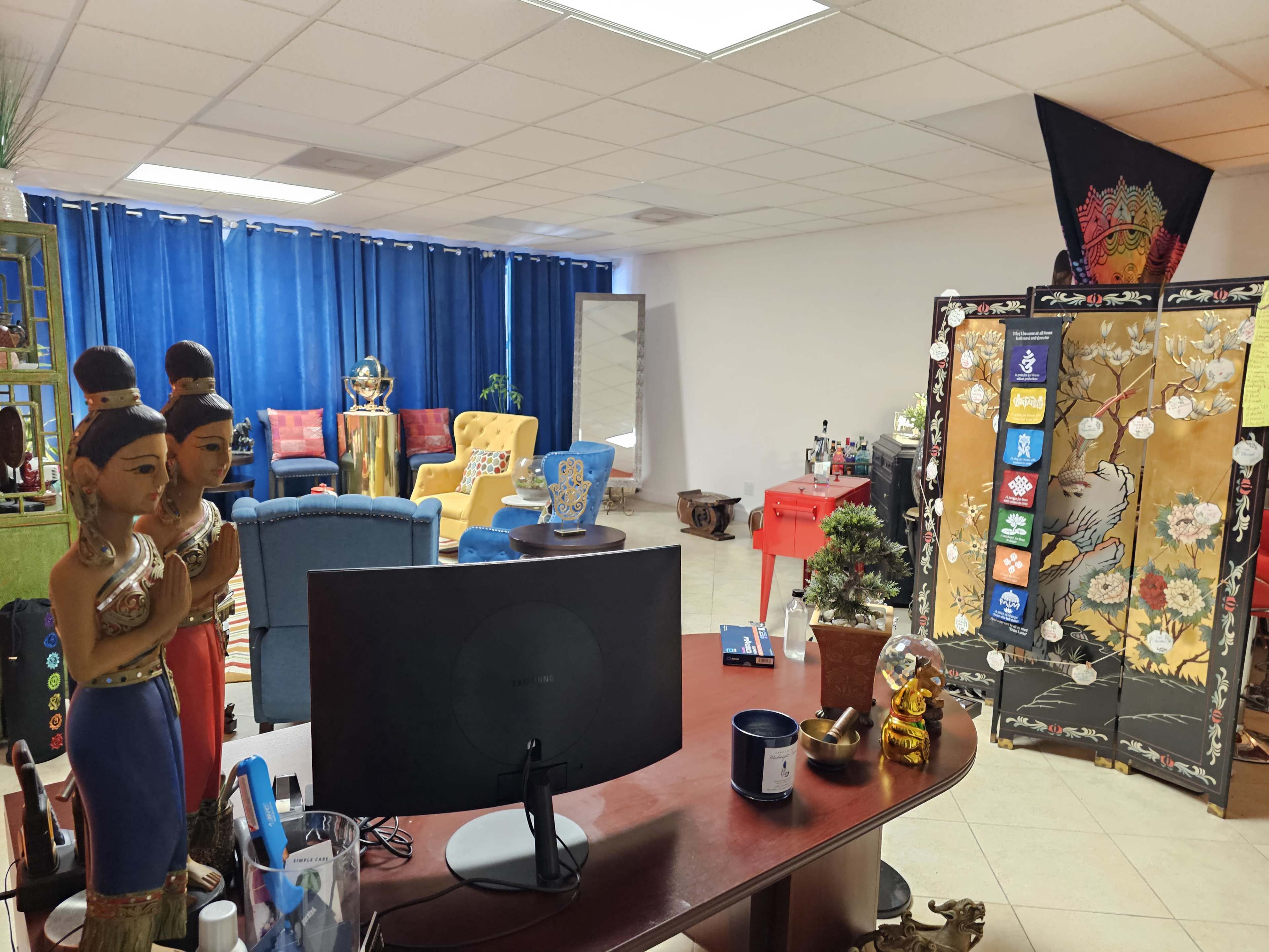 A colorful, creatively decorated room featuring various seating arrangements, decorative statues, and a divider with intricate designs.