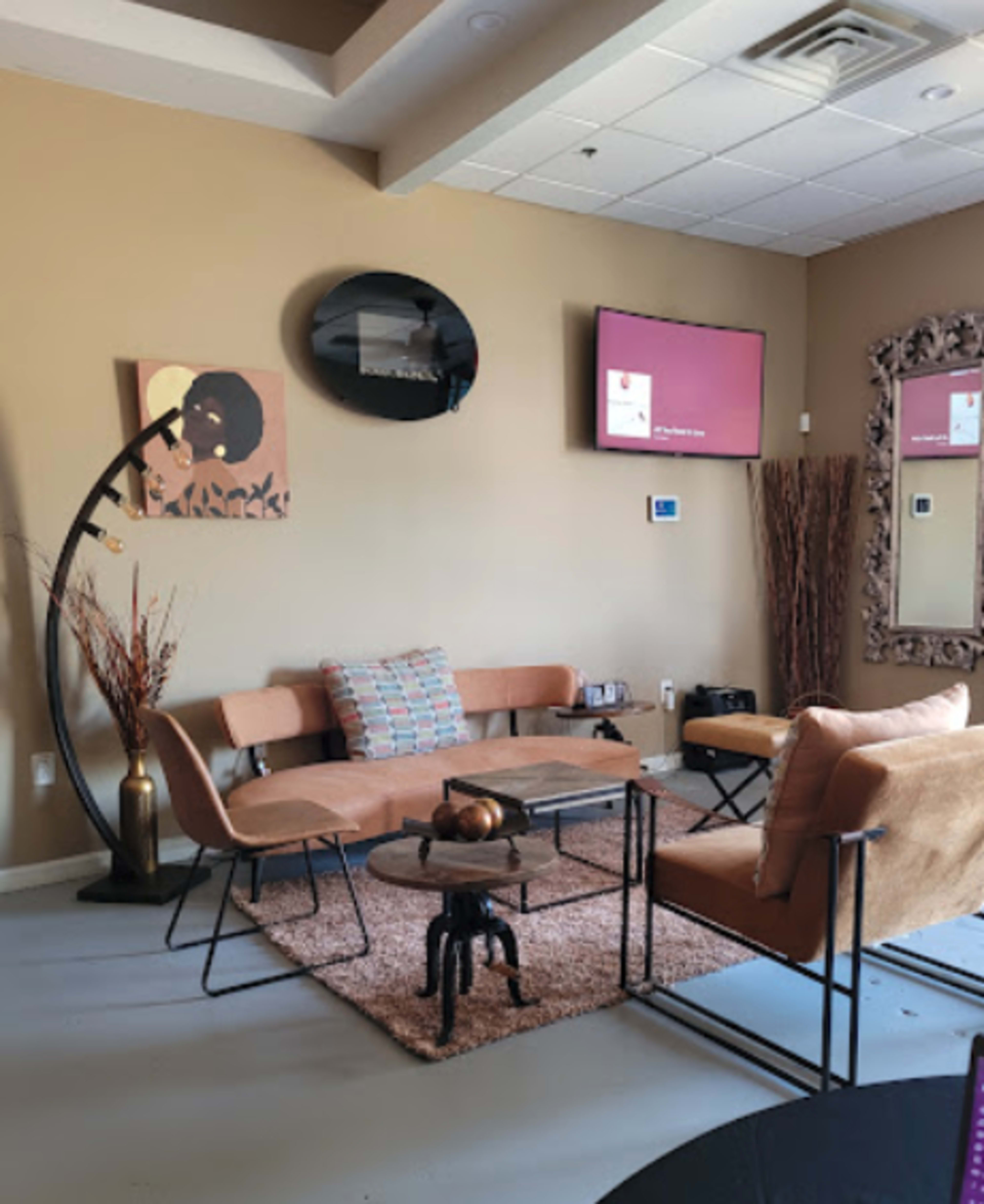 A modern interior living space with a brown sofa, a large mirror, and a TV mounted on the wall.